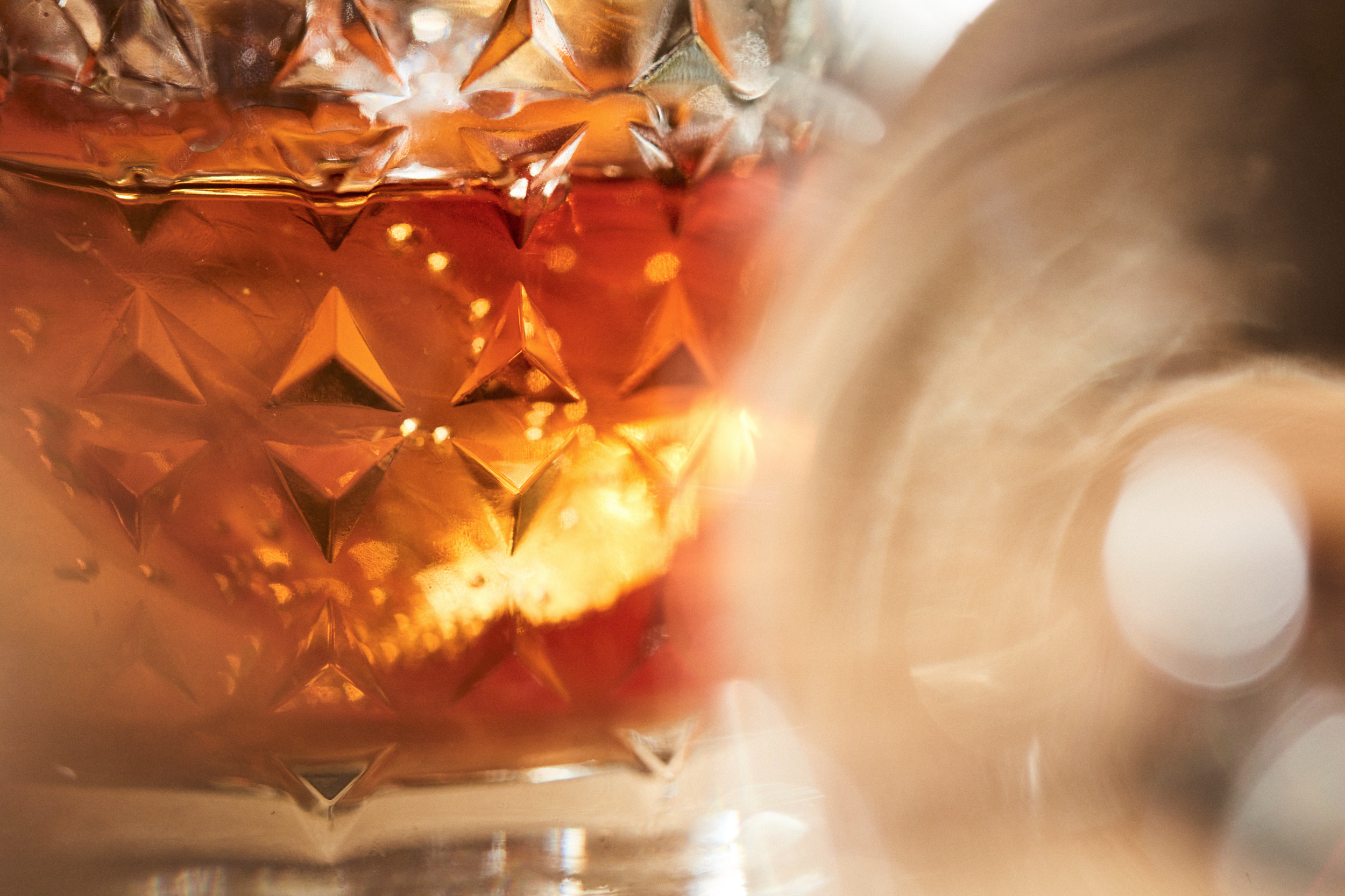Close-up of an orange, textured, star-patterned Christmas ornament with reflections of warm lights.