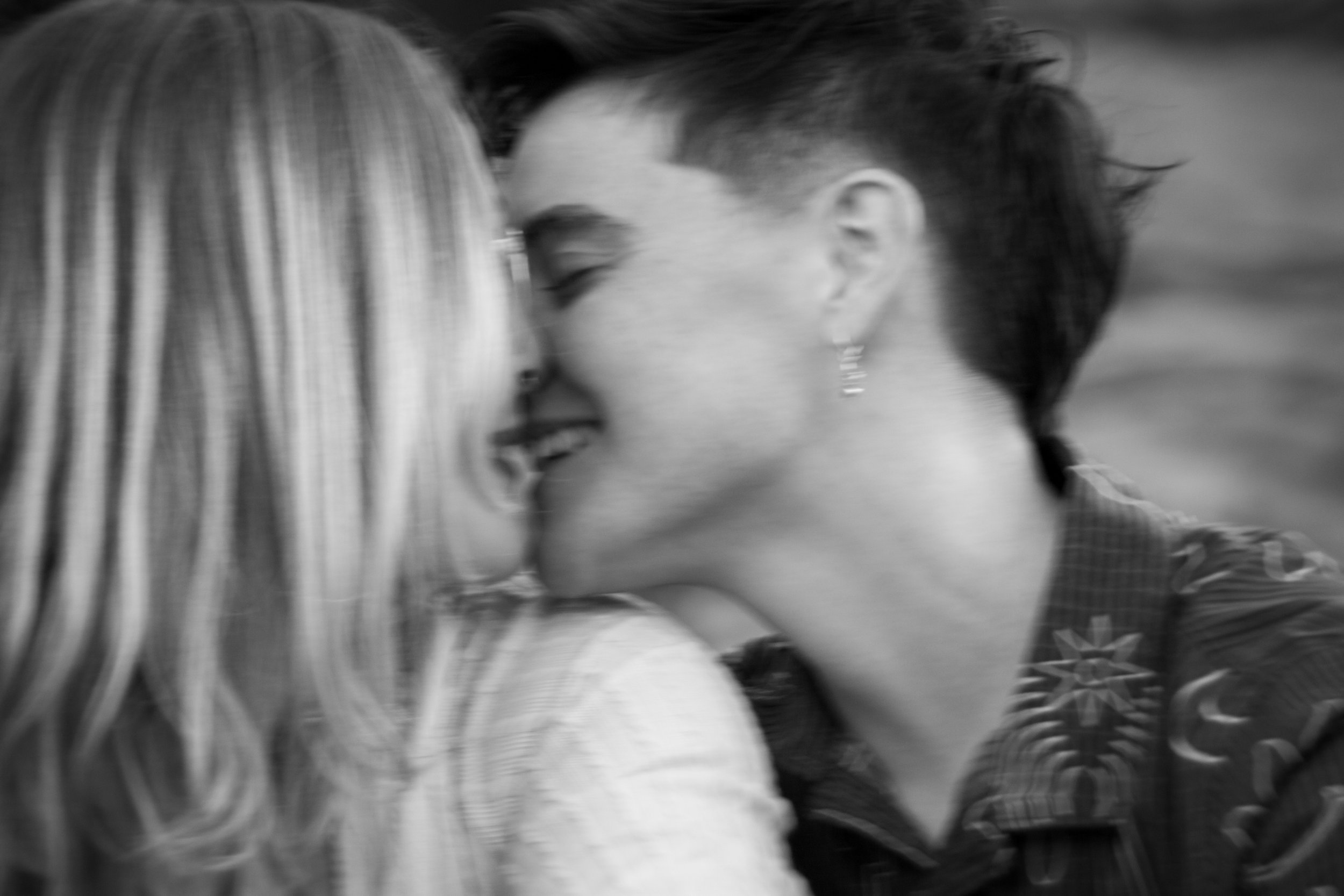 Black and white photo of a couple leaning in close, about to kiss, with their faces just touching and their eyes closed.