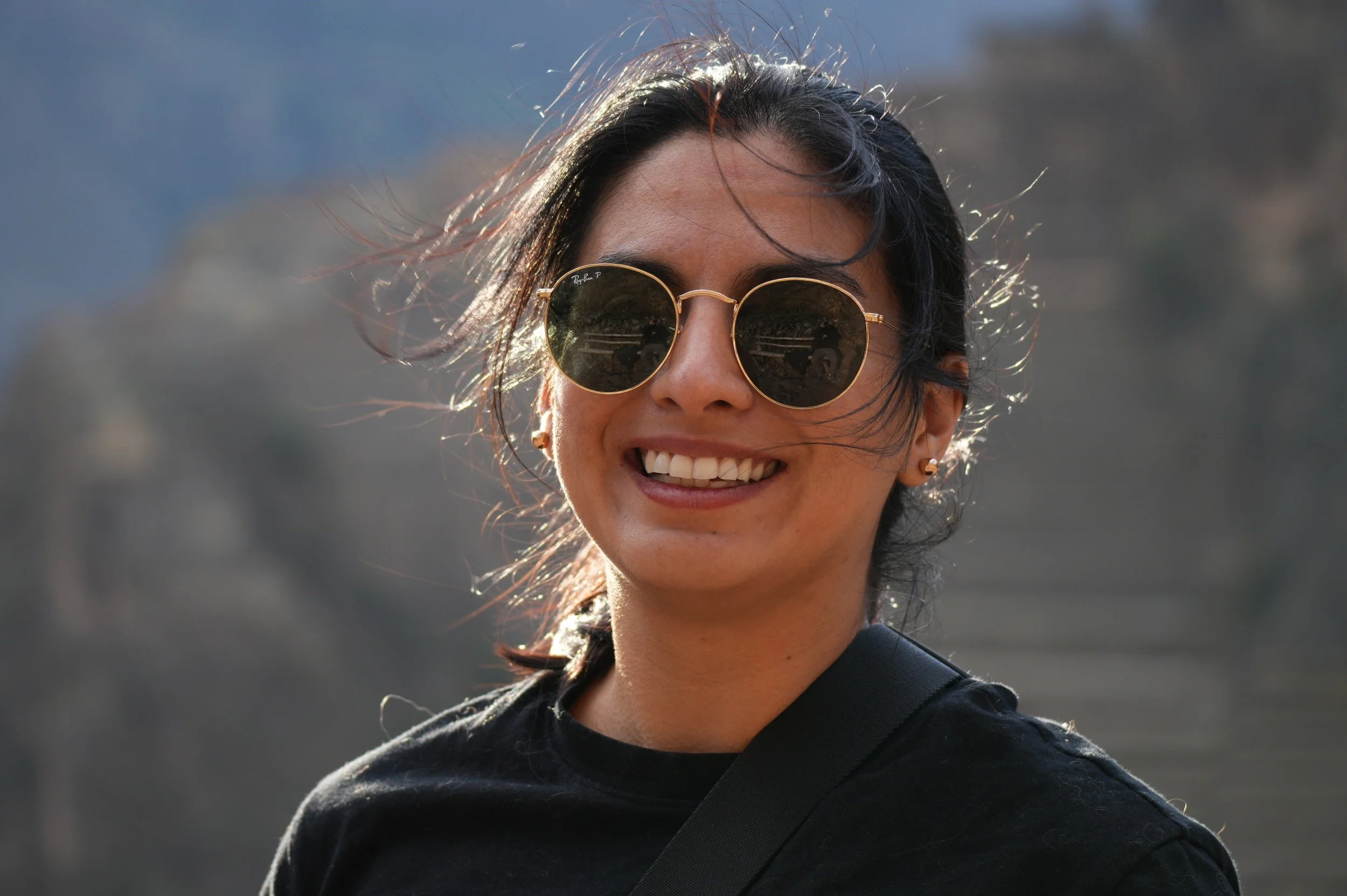 Andrea wearing sunglasses with a mountain backdrop.
