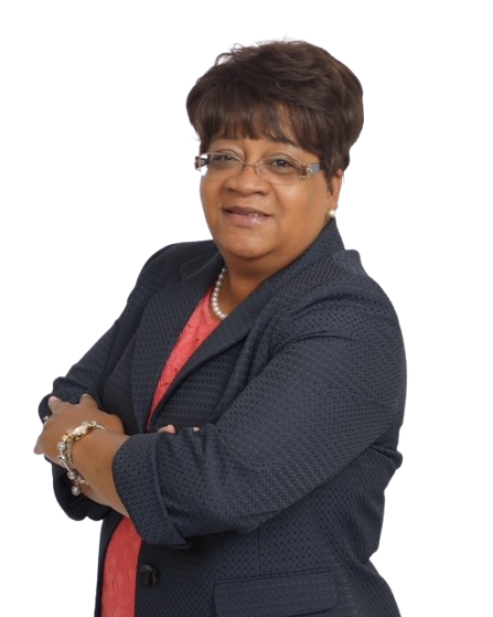 A woman with short hair and glasses wearing a navy blazer over a red top, standing with arms crossed.