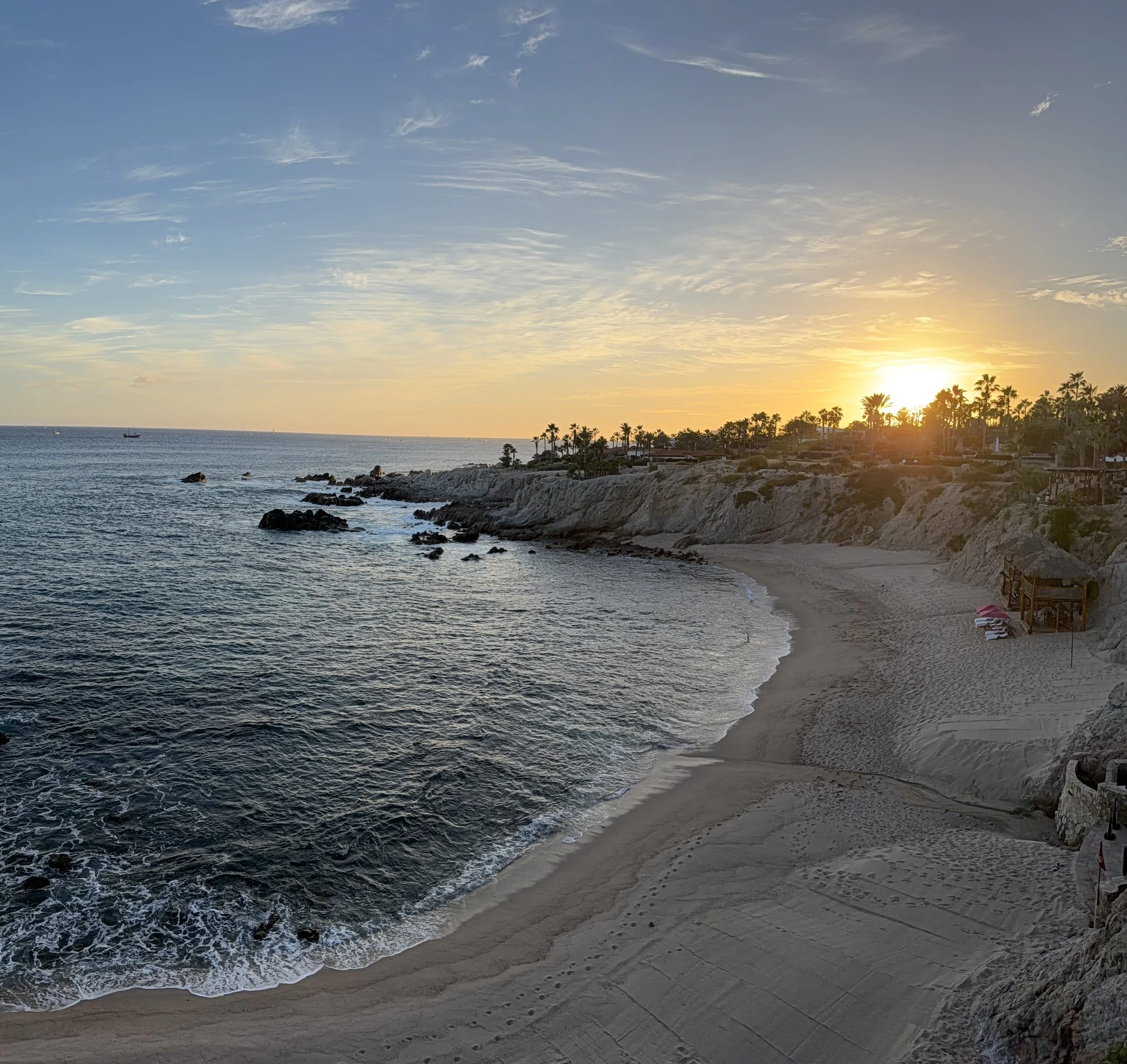 Golden sunset over a rocky coastal beach with calm ocean waves, evoking the scenic destination events planned by Obsidian Opal Events