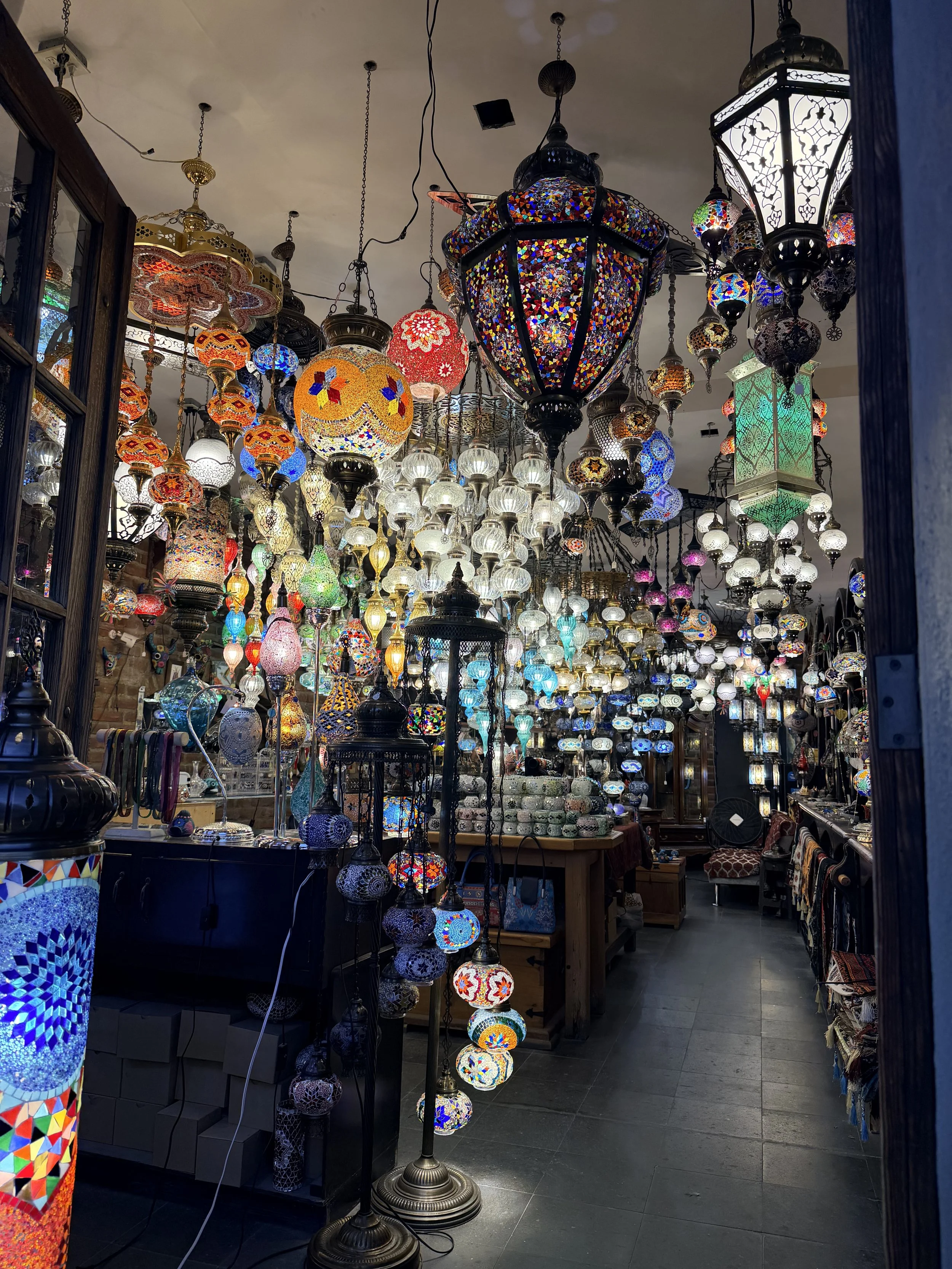 Vibrant collection of colorful mosaic lanterns and decorative lights displayed in a market, inspiring event décor ideas for Obsidian Opal Events