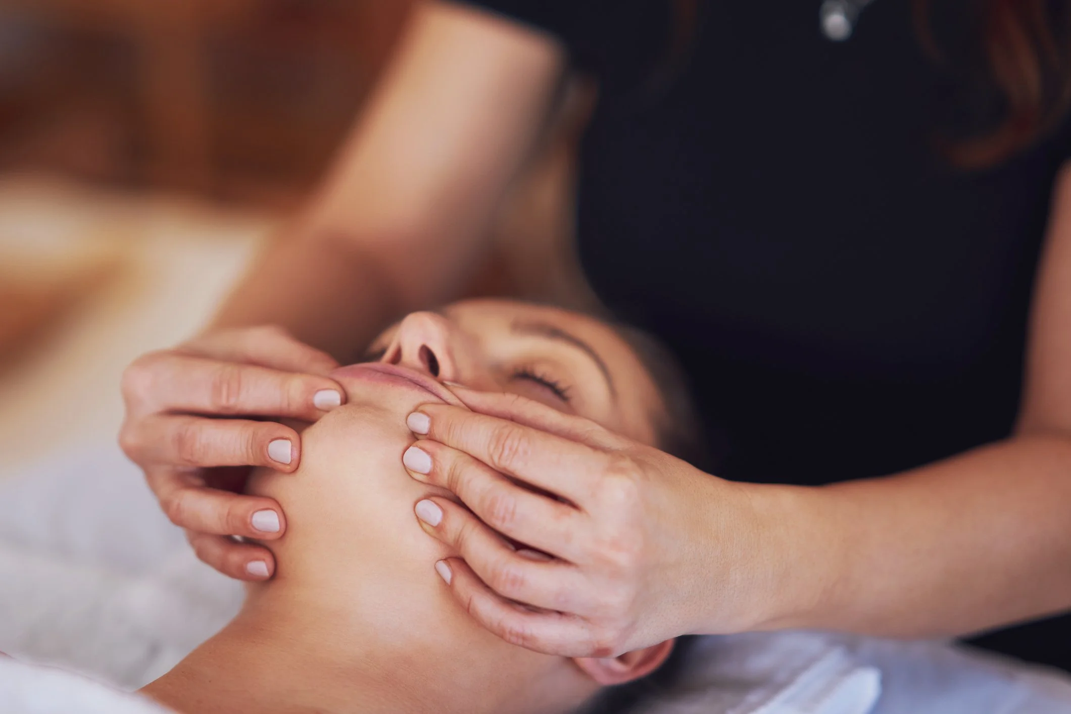Person receiving a facial massage or skincare treatment in a spa or salon.