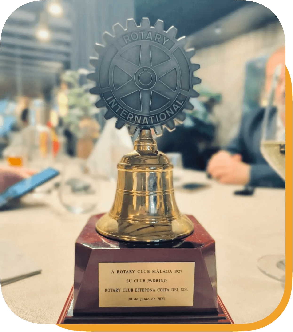 Trofeo de un club rotario con un engranaje y la palabra 'ROTARY' en su interior, colocado sobre una base de madera con una placa que indica que fue para el Club Rotario Málaga 1927, entregado en una reunión el 20 de junio de 2023.