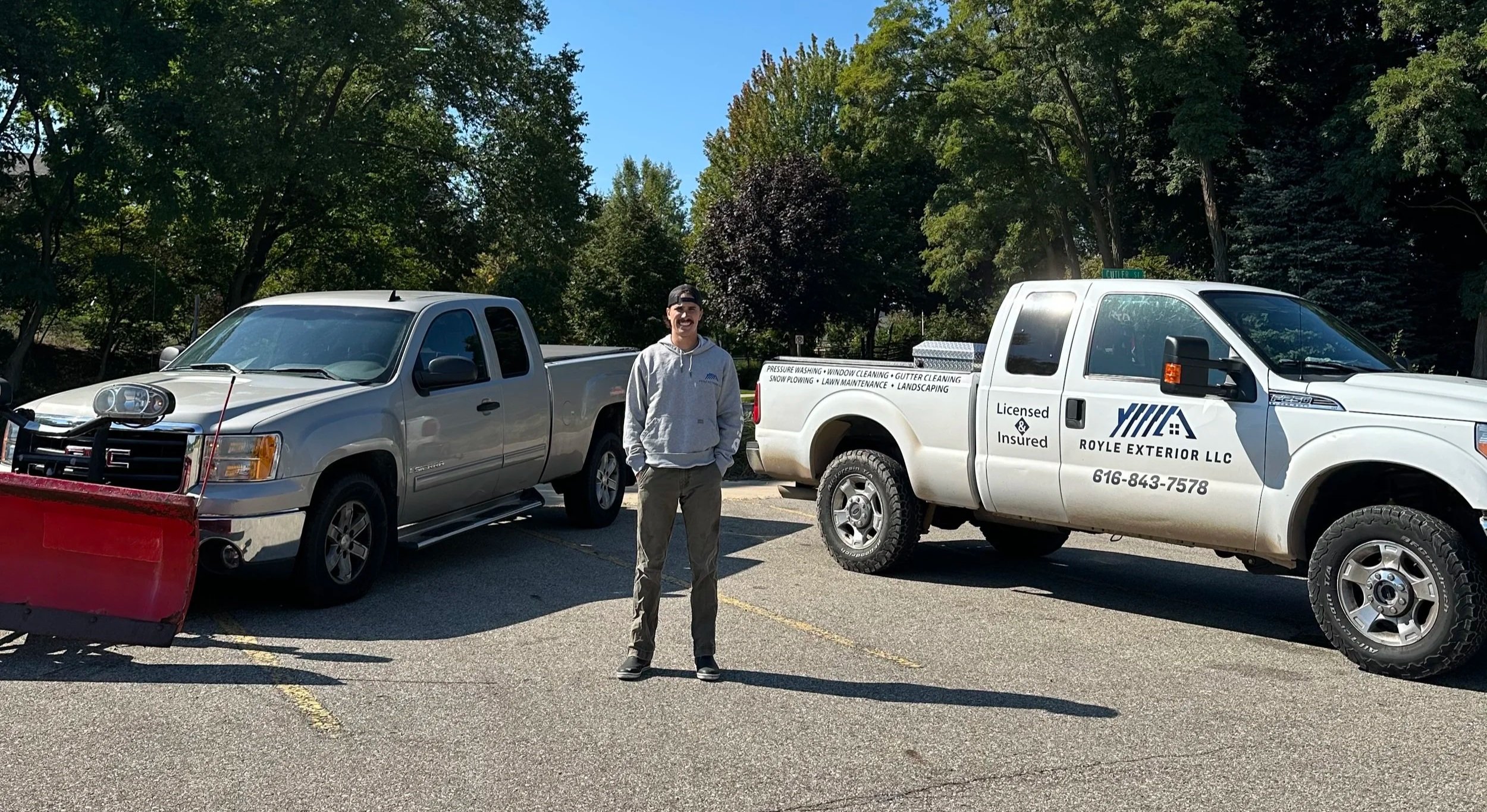Matthew Bradford-Royle (owner) standing in front of vehicles, including a white pickup truck with cleaning and landscaping services, and a gray van with a snowplow attachment with Royle Exterior logos