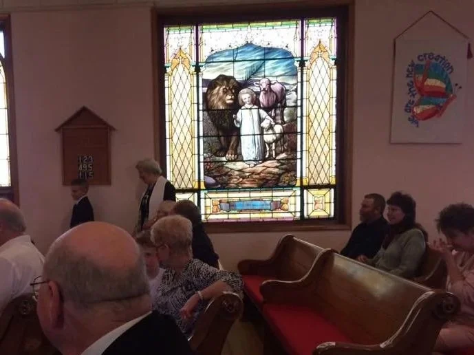 The love between church members is intended to model what God wants for all people, God's own aspiration for the whole world. The window portrays Isaiah 11 and God's promise to someday restore the Garden of Eden.