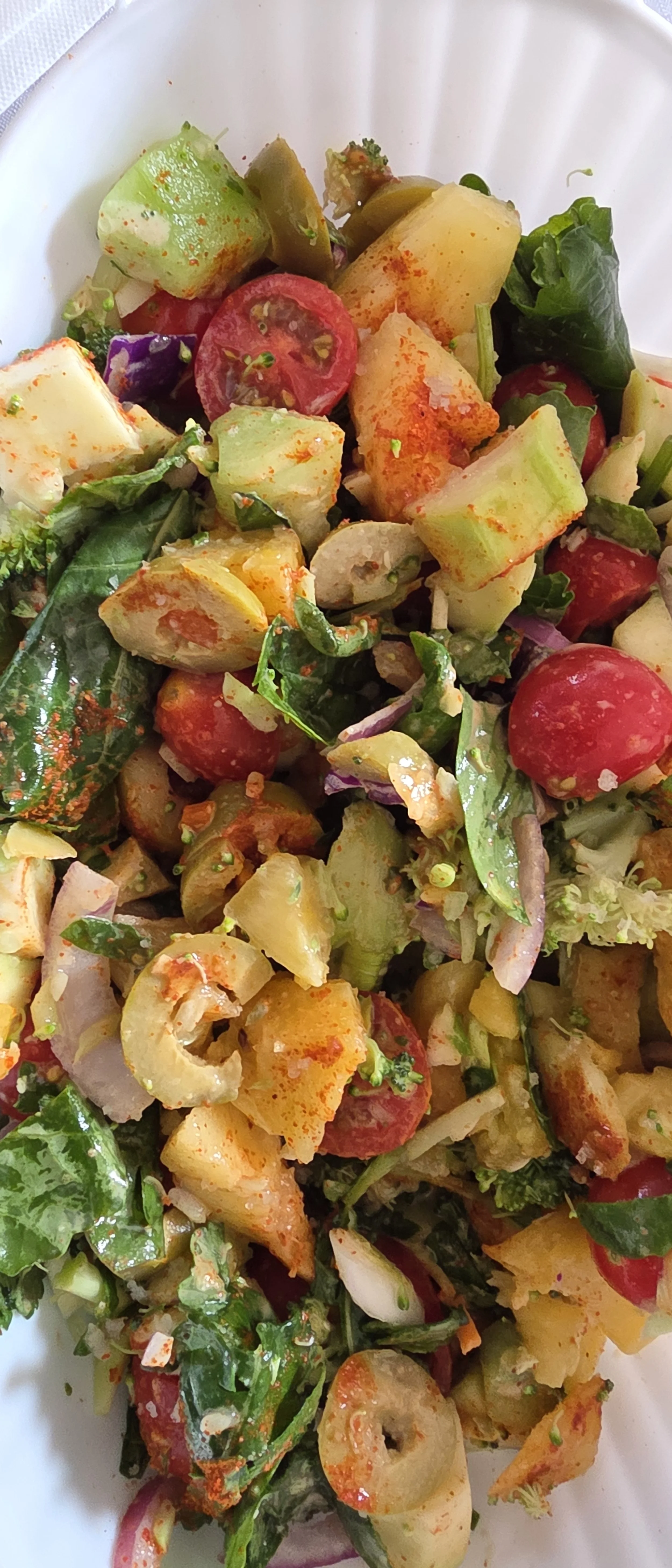 Close-up of a mixed fruit and vegetable salad with cherry tomatoes, celery, spinach, and other chopped vegetables.