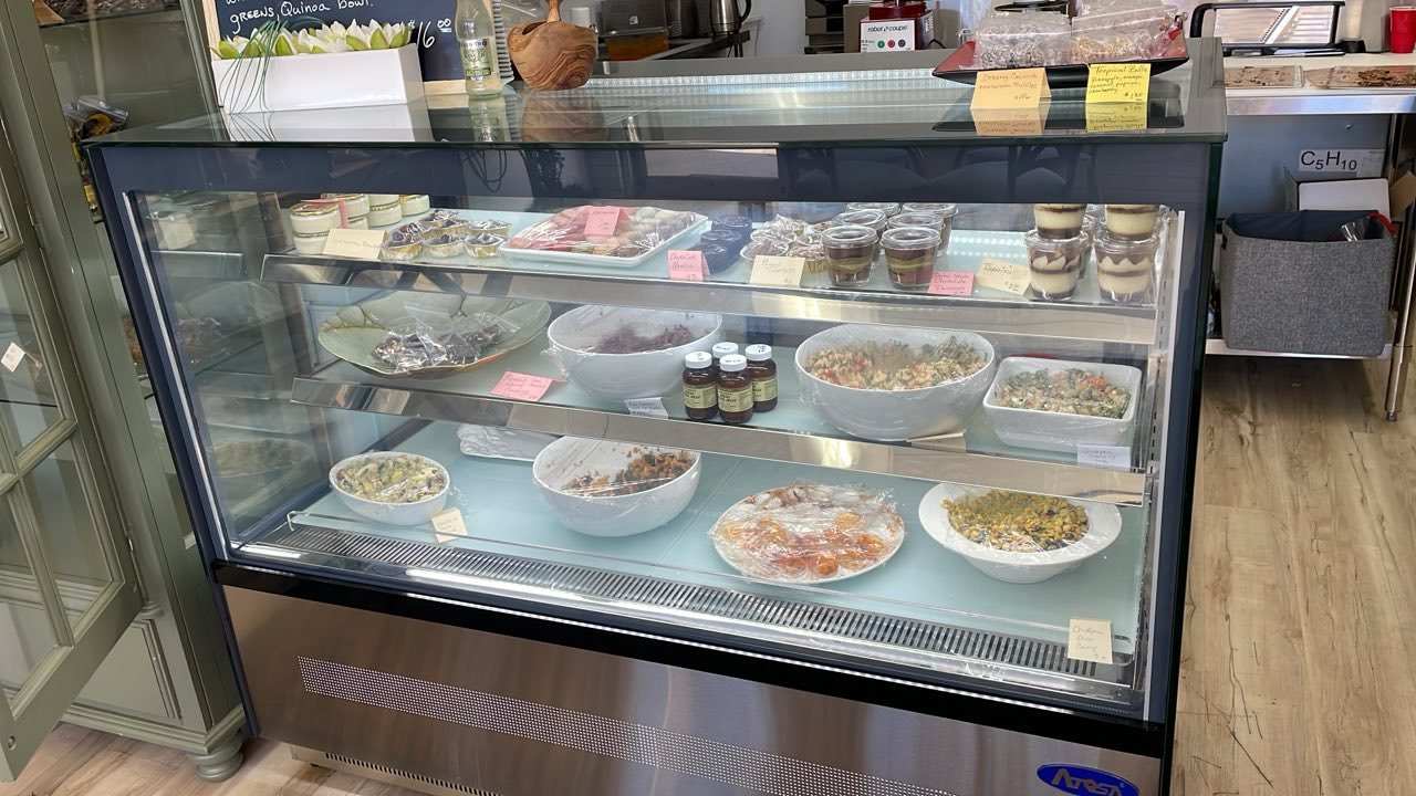 Food display case filled with various salads, desserts, and other treats.