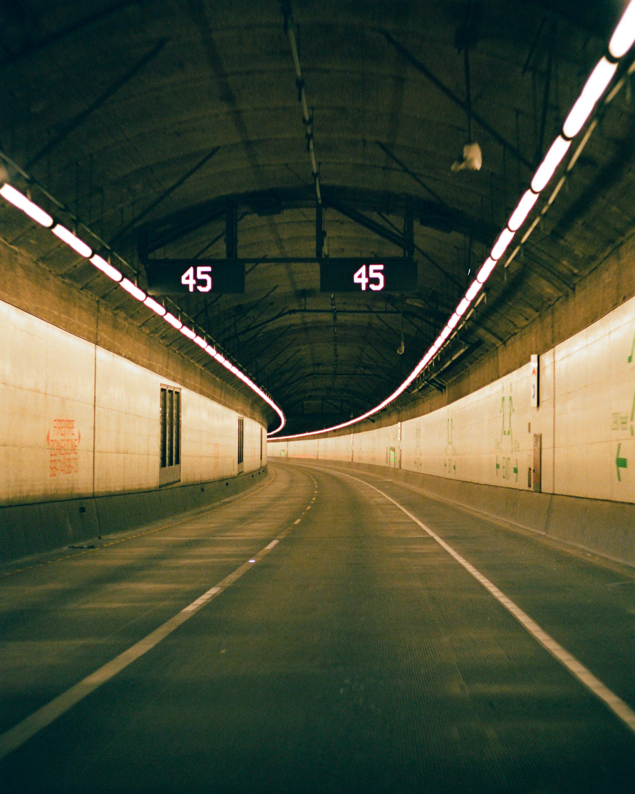 A tunnel with illuminated lane markers and a digital speed limit sign displaying 45 mph.