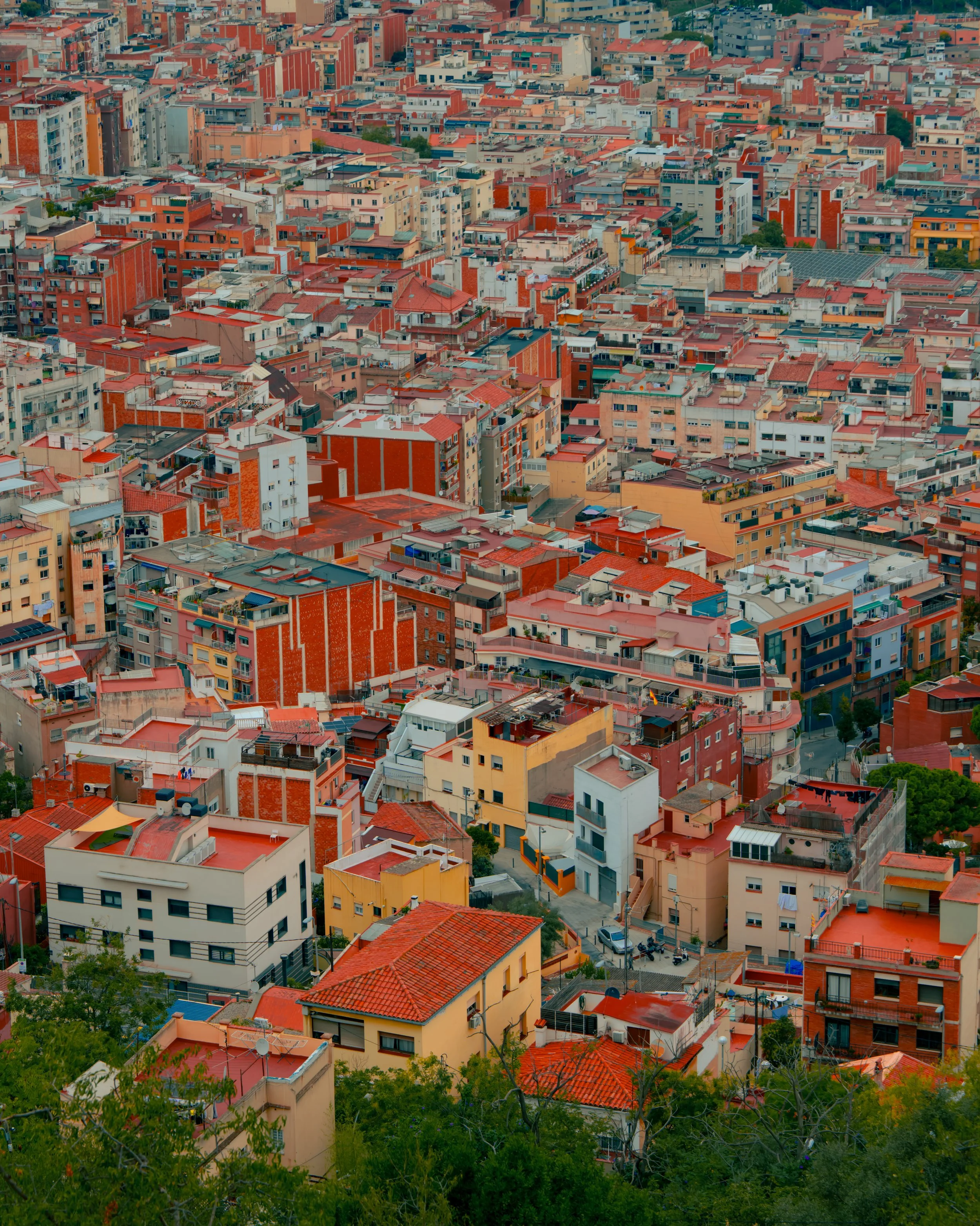 Aerial view of densely packed buildings with red and orange rooftops in a cityscape.