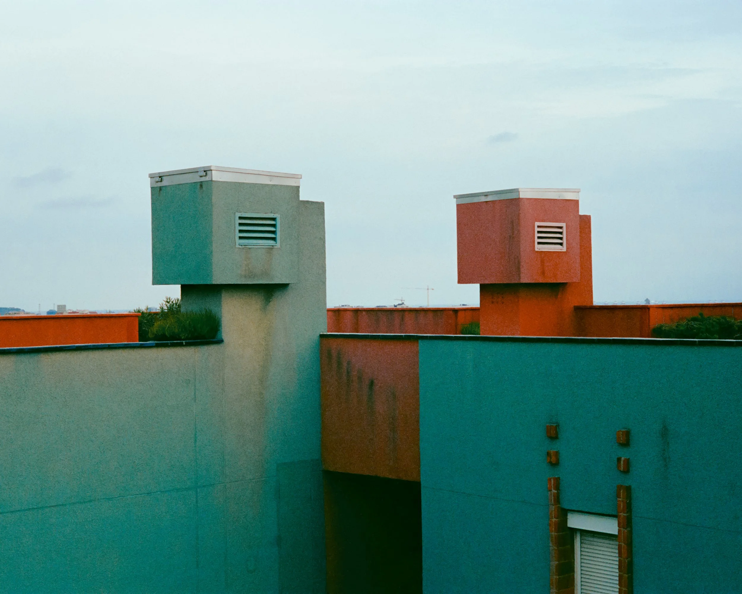 Colorful rooftop with two vents, one green and one red, against a cloudy sky.