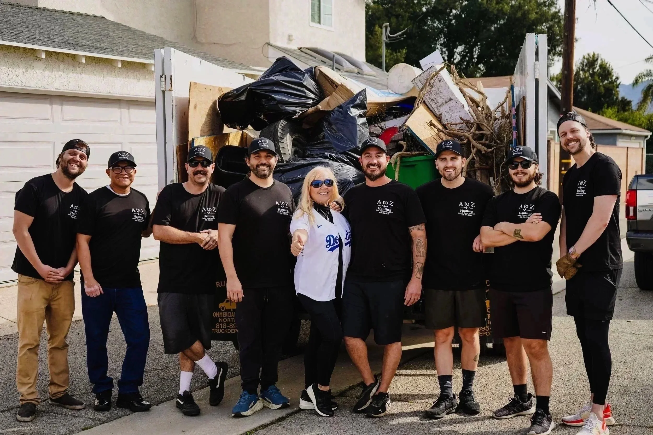 A to Z Hauling junk removal team in Burbank, CA standing in front of a truck filled with debris after a cleanout job.