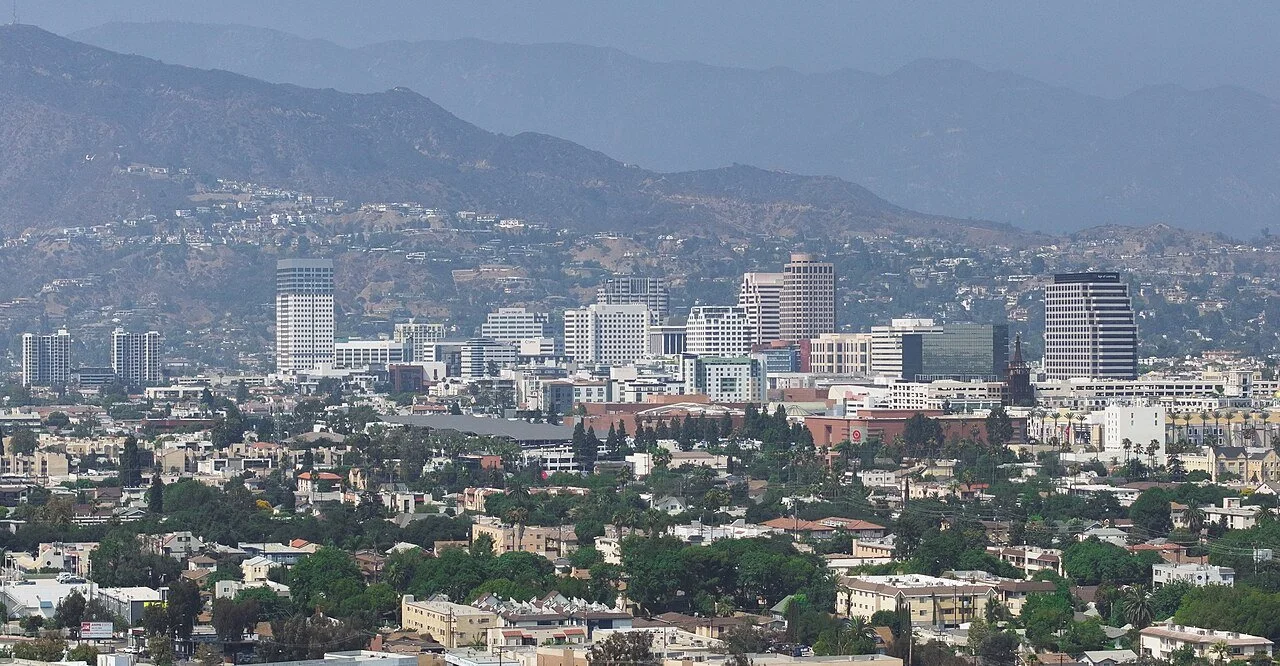 City skyline with high-rise buildings and mountains in the background.