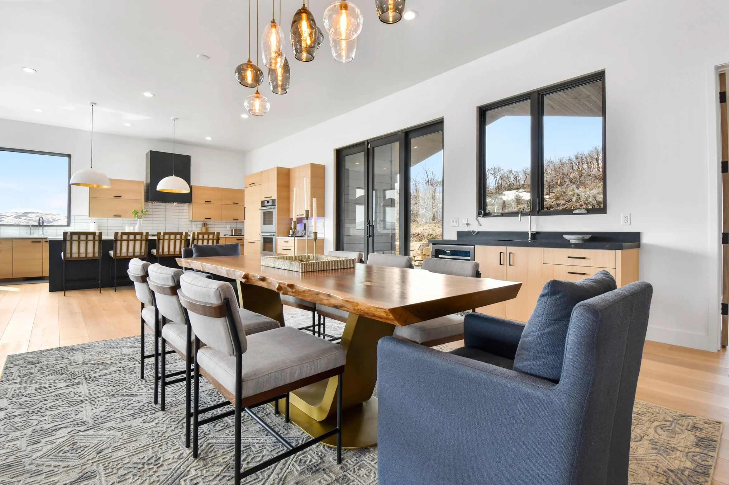 a live edge walnut dining room table on a "U" shaped gold plated steel pedestal base in a bright contemporary home