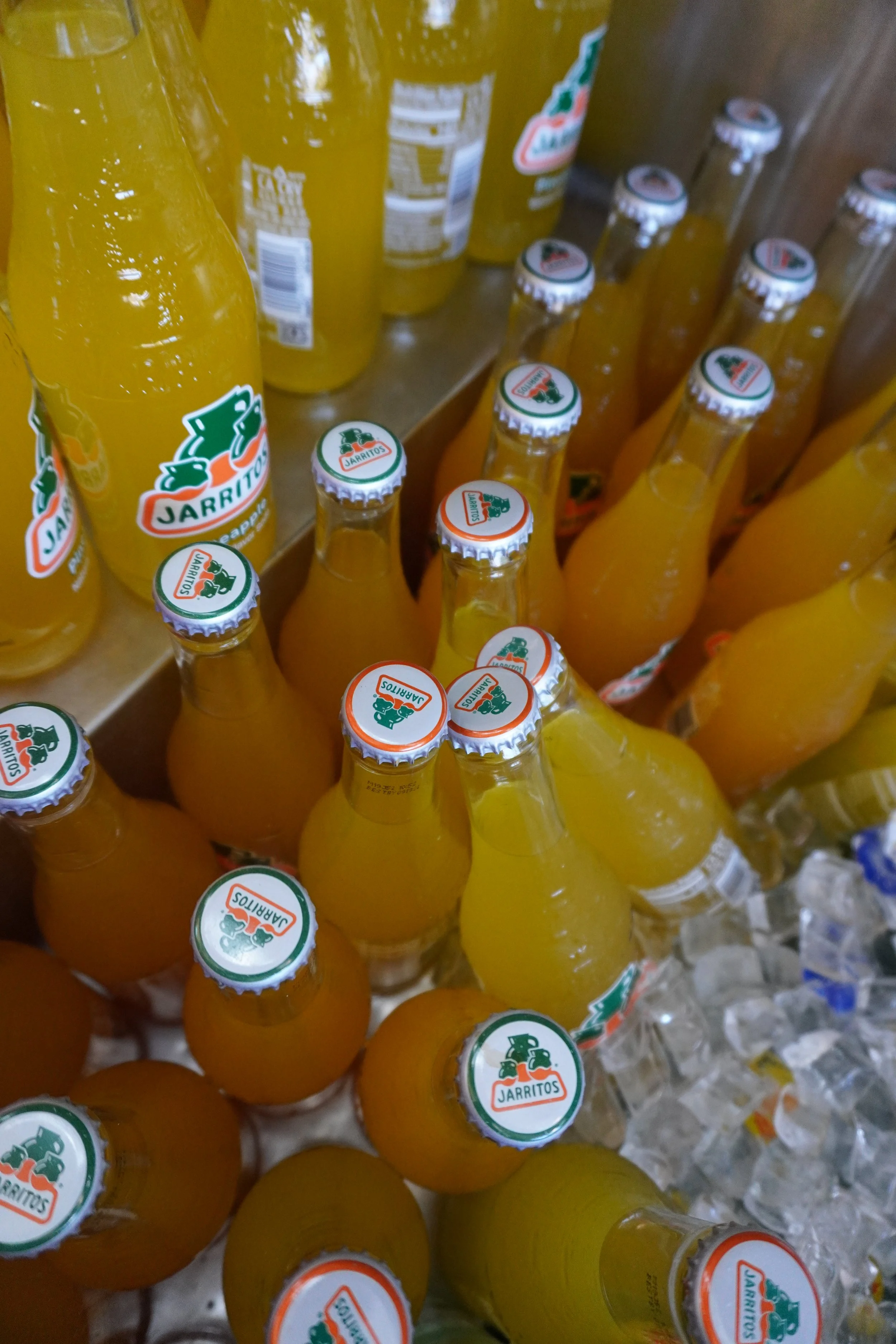 Multiple bottles of Jarritos pineapple soda in a display with ice.