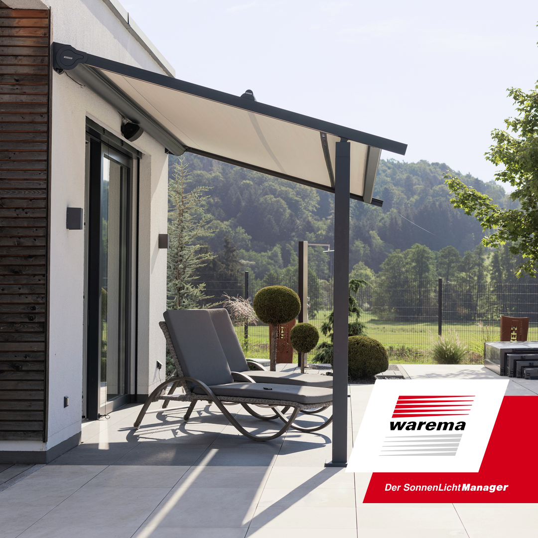 Modern outdoor patio with two lounge chairs, a retractable awning, potted topiary plants, and a scenic view of a green landscape with trees and hills.