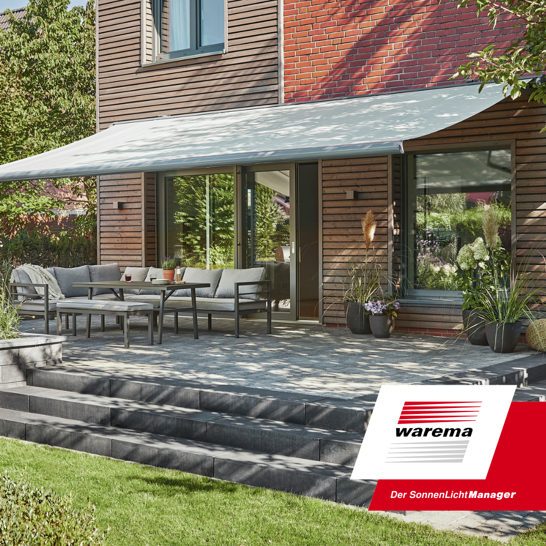 A modern patio with outdoor furniture, potted plants, and a retractable awning in a residential backyard.