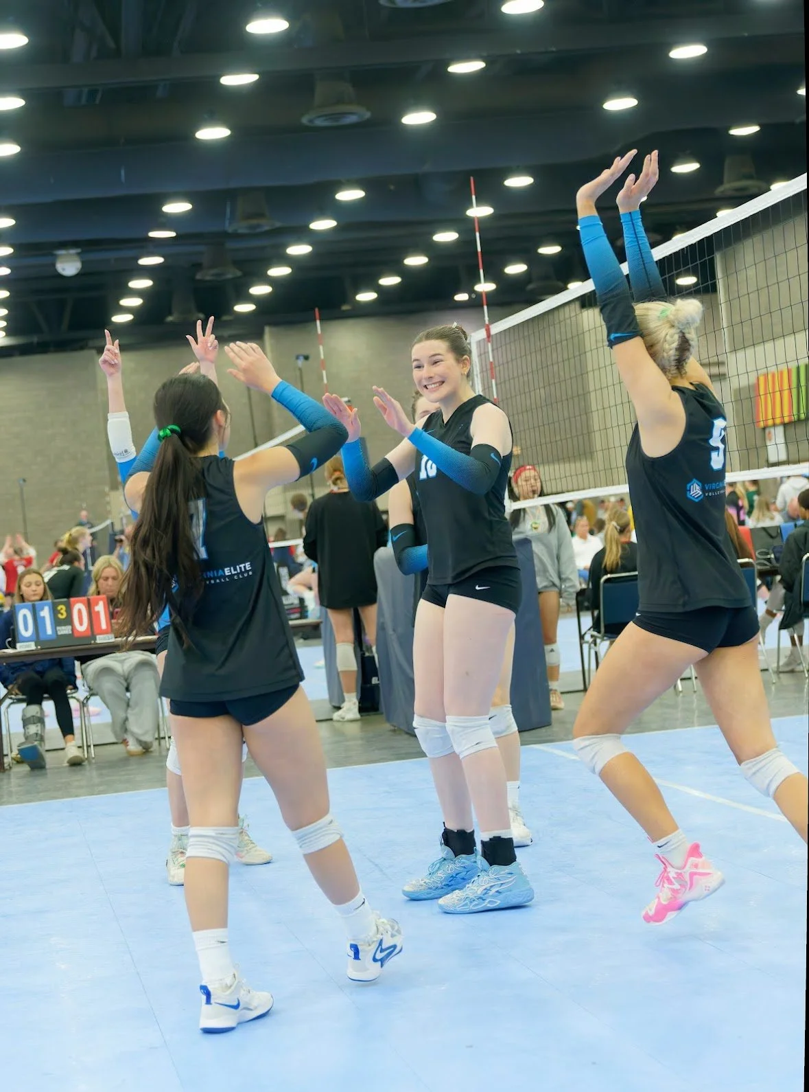 Girls volleyball players celebrating on the court during a game.