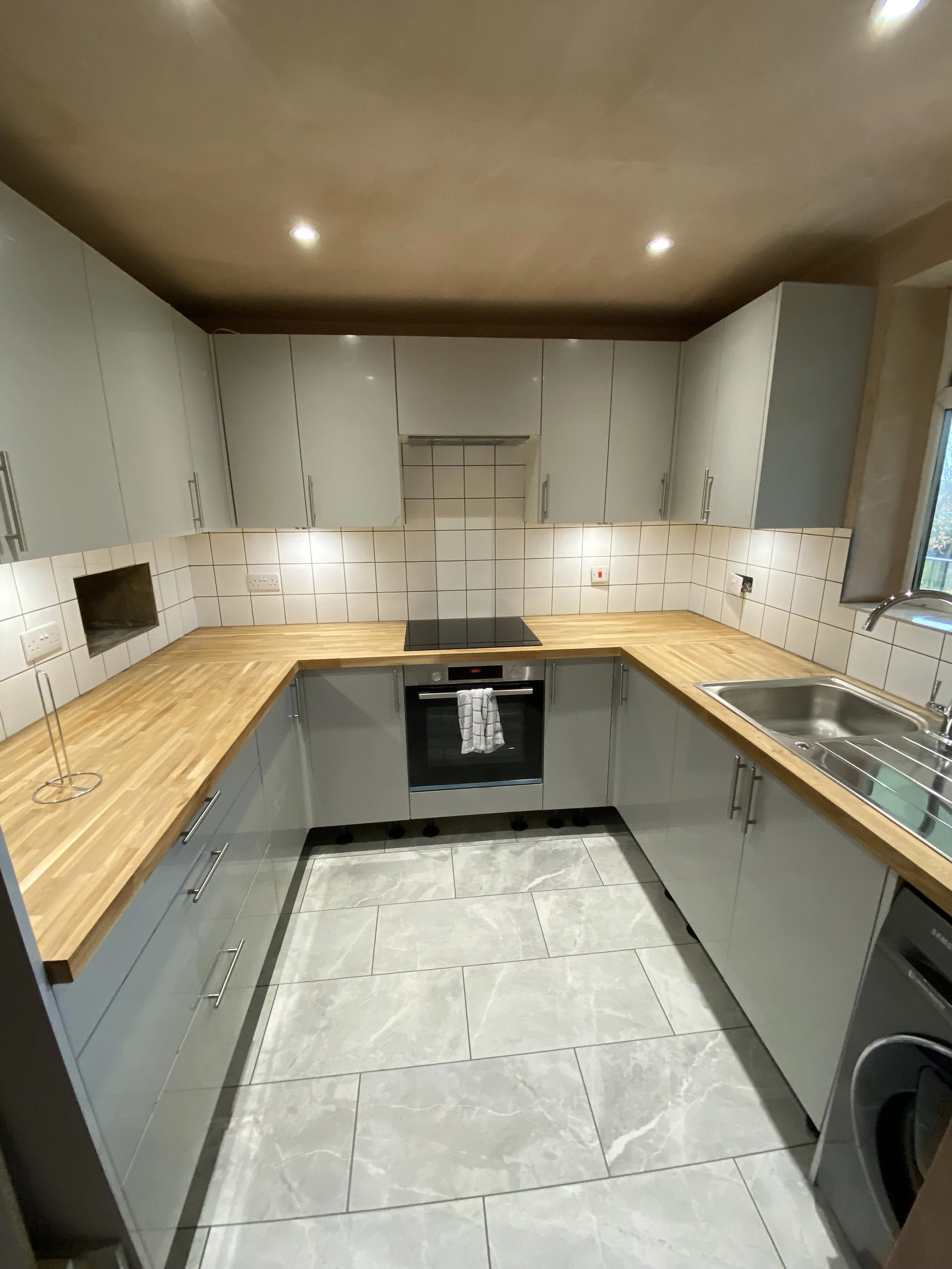 Newly refurbished kitchen with sleek fitted units, upgraded worktops, modern splashback tiling, and bright ceiling spotlights.