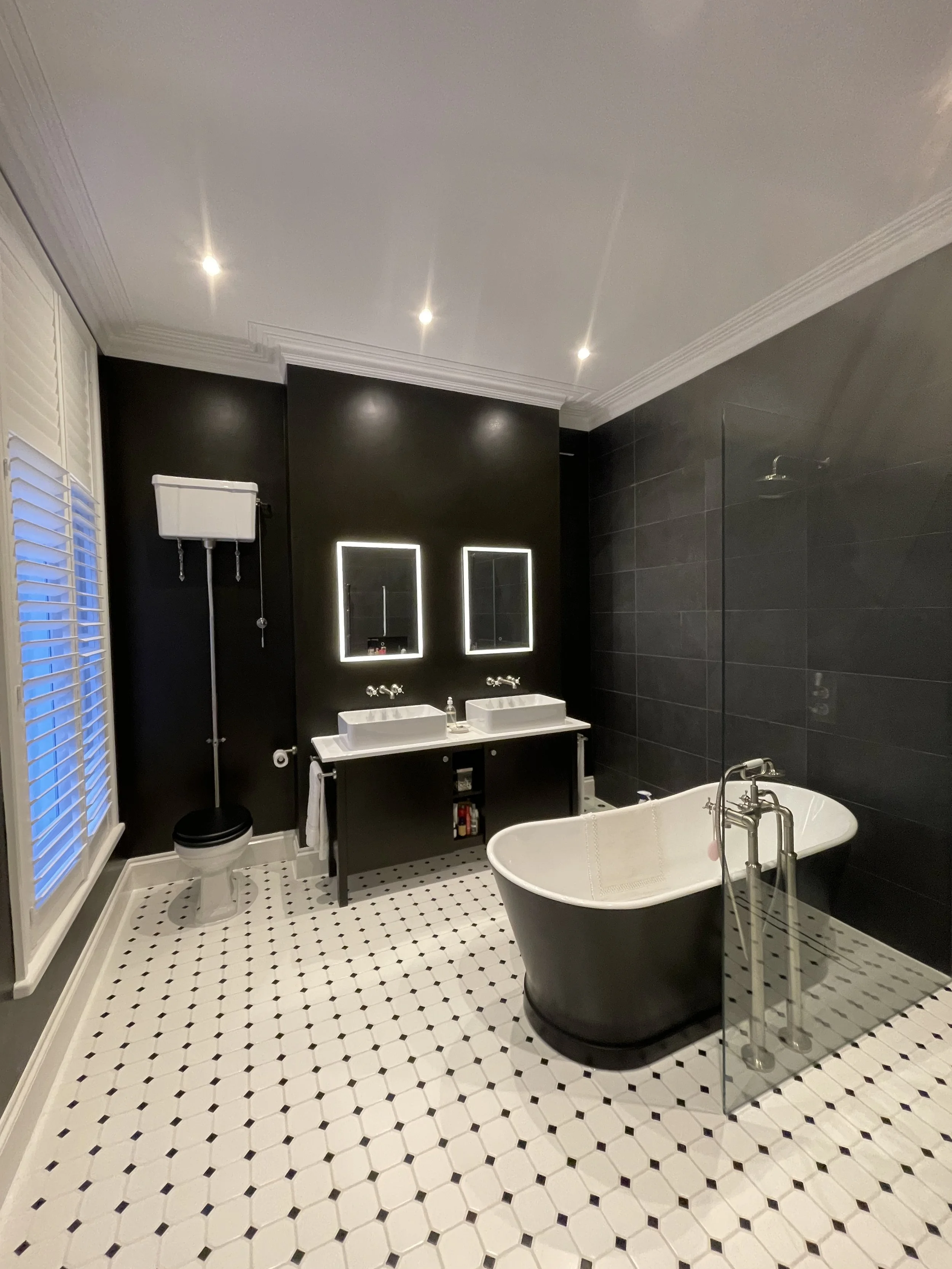 Luxury bathroom remodel with marble-effect tiles, glass shower screen, vanity unit, and heated towel rail.