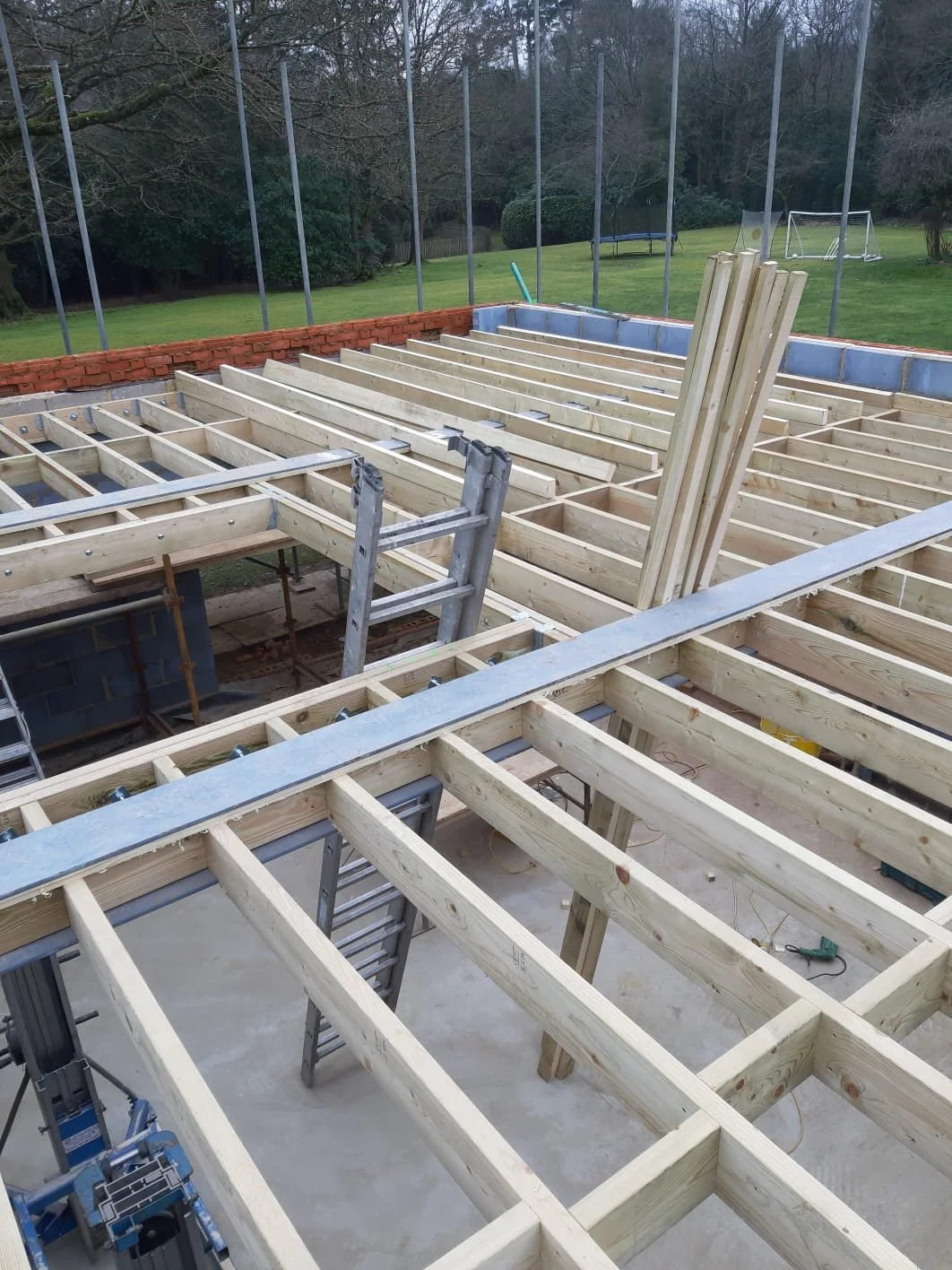 Structural timber roof with long-span beams supporting roof joists for a garden outbuilding