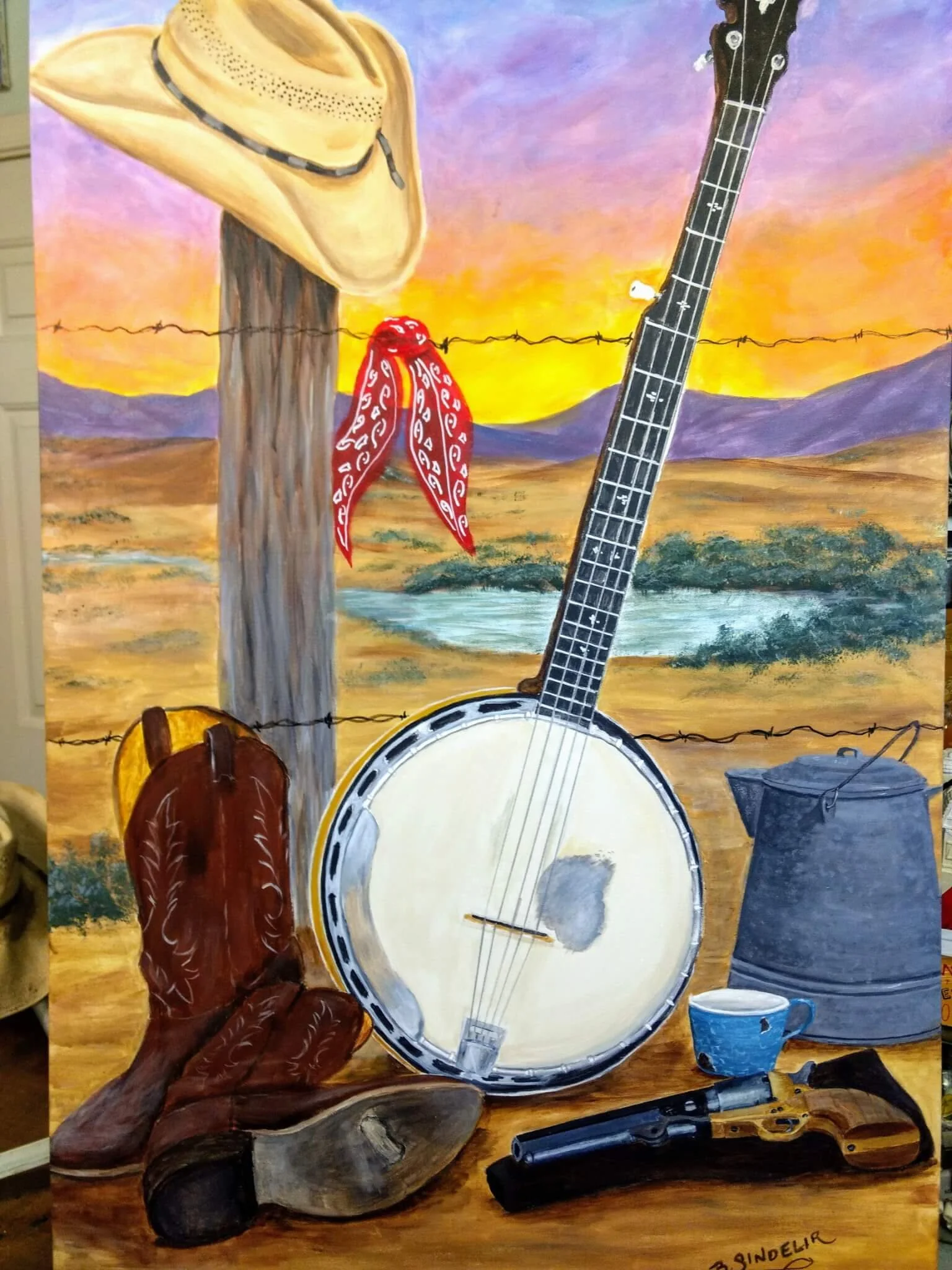 A painted outdoor scene with a straw cowboy hat hanging on a wooden post, a red bandana tied around the post, a banjo, brown cowboy boots, a gun, a blue cup, a metal bucket, and a small knife, all set against a desert landscape with mountains and a s