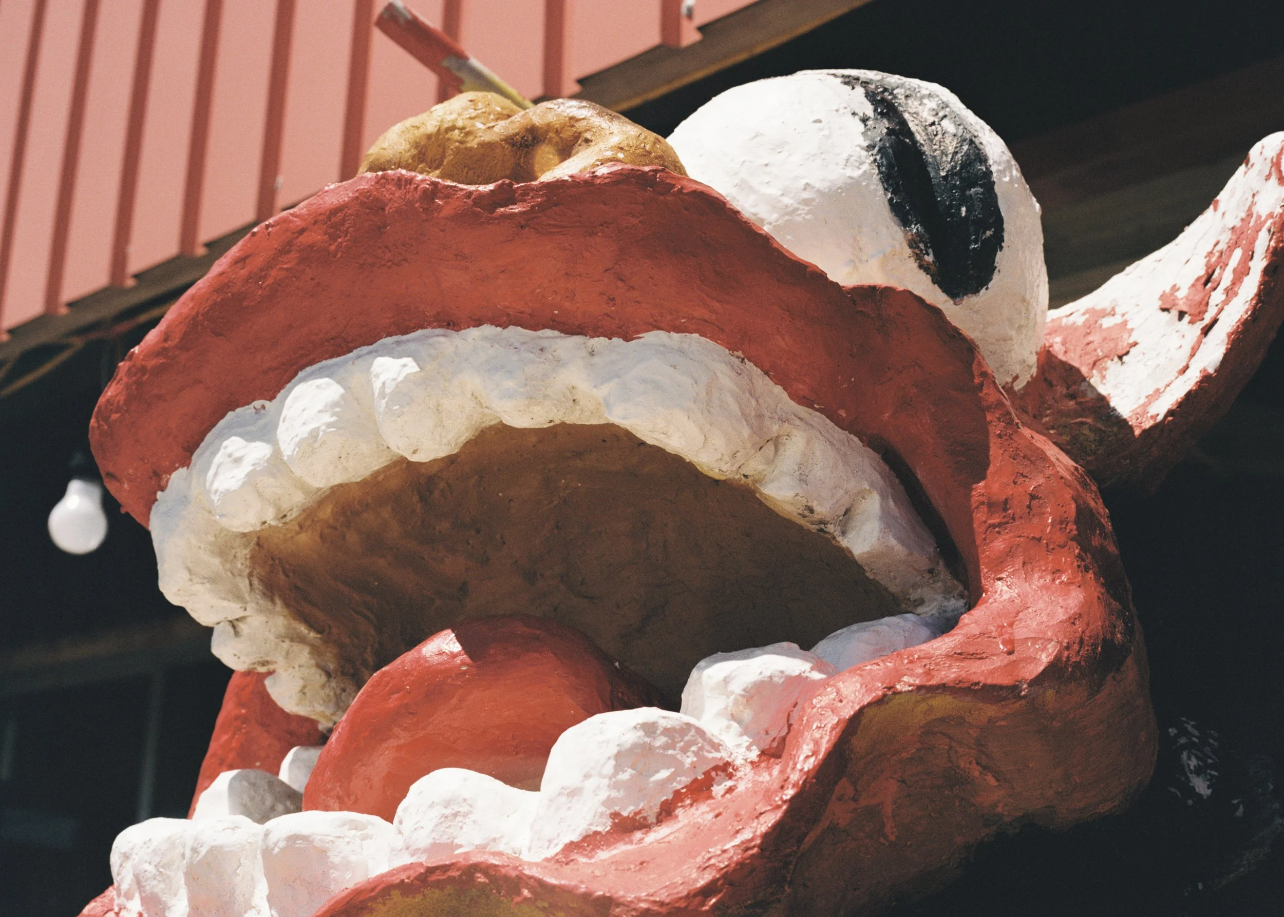 A large sculpted Santa Claus head with a red hat and white beard, with a nautical buoy painted white and black behind it.