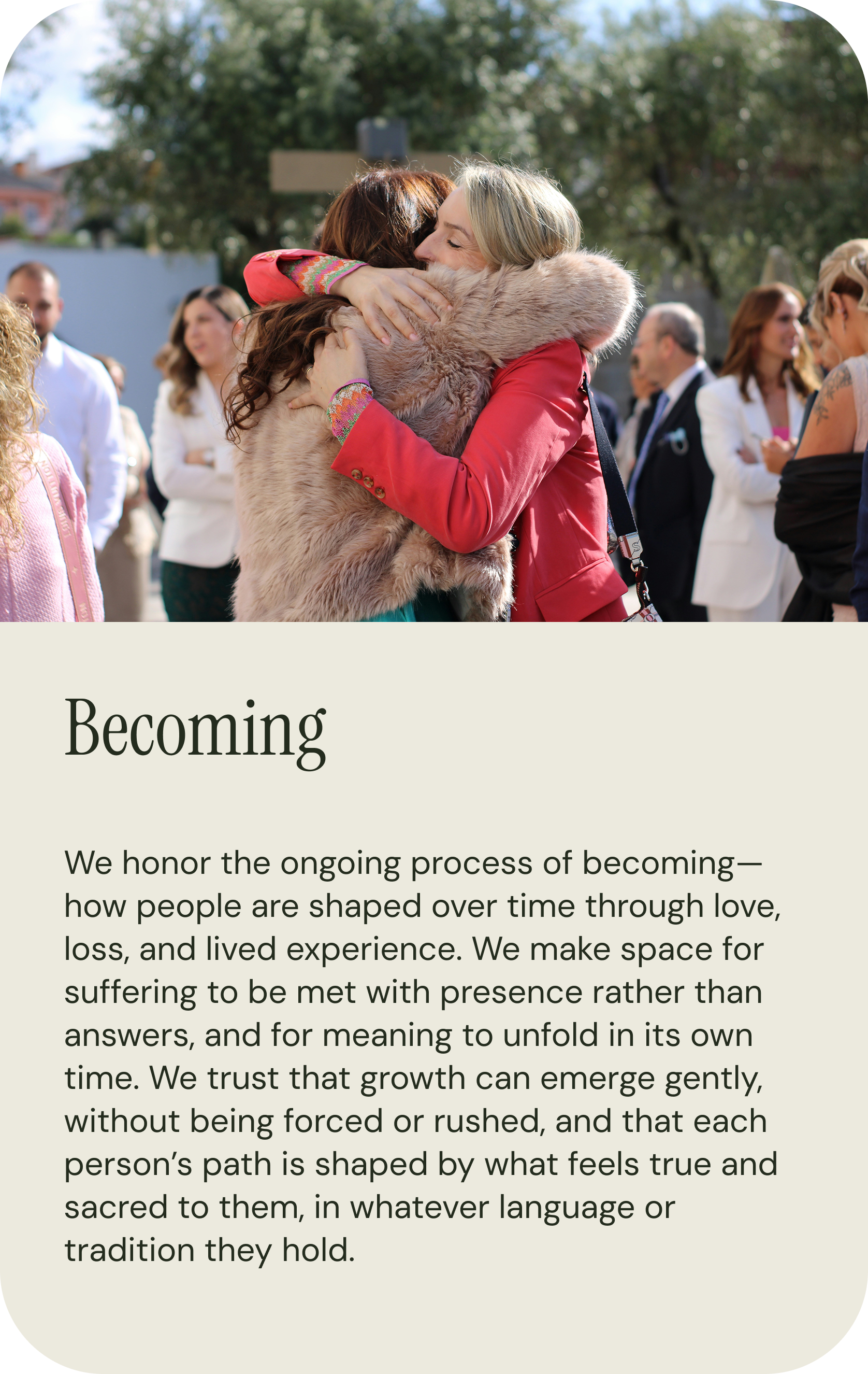 Two women hugging at an outdoor gathering, with other people in the background.