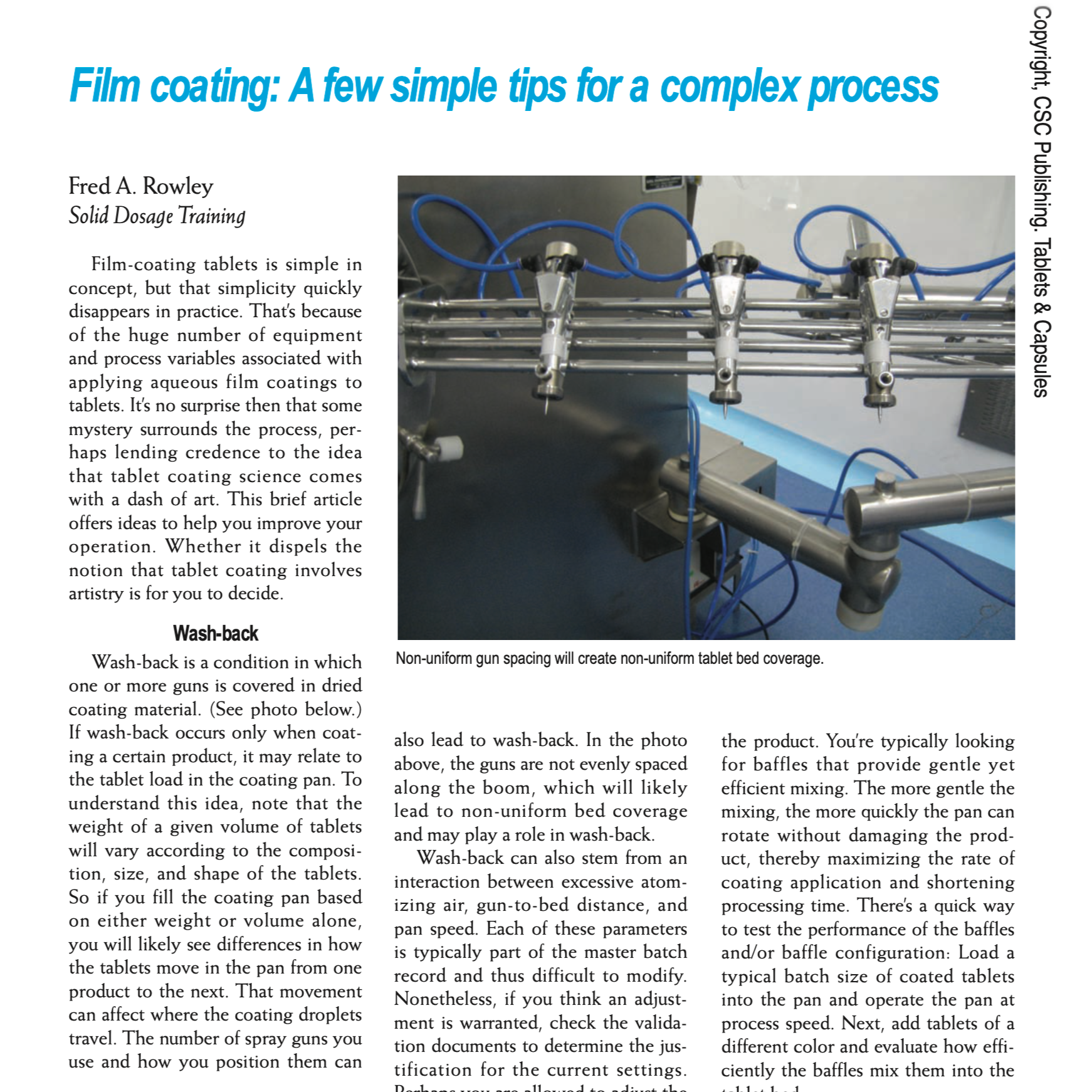 Photo of a film coating machine with multiple spray guns, blue hoses, and metallic pipes, used in pharmaceutical tablet coating processes.