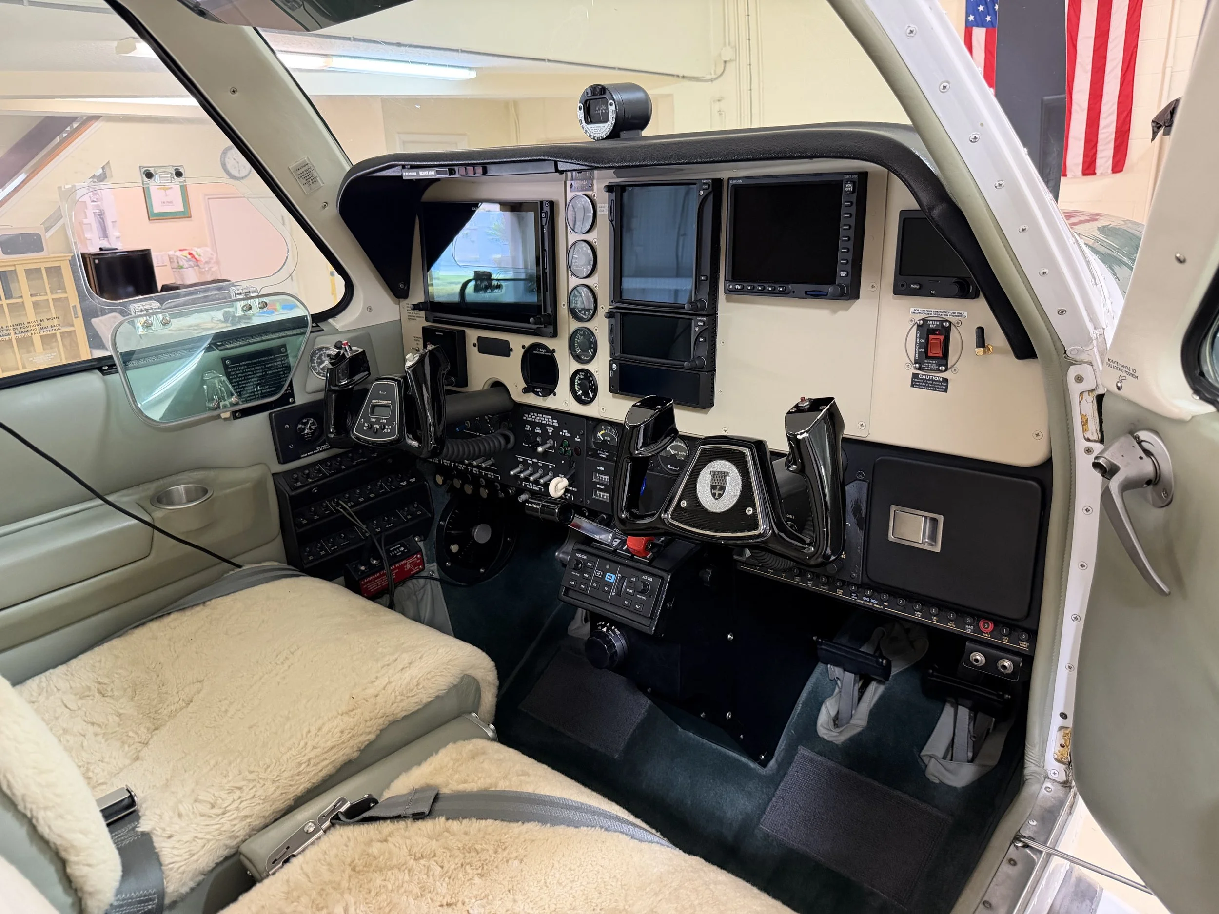 View of the cockpit inside a small airplane, showing instrument panels, control yokes, a radio, digital screens, switches, and a cushioned seat.