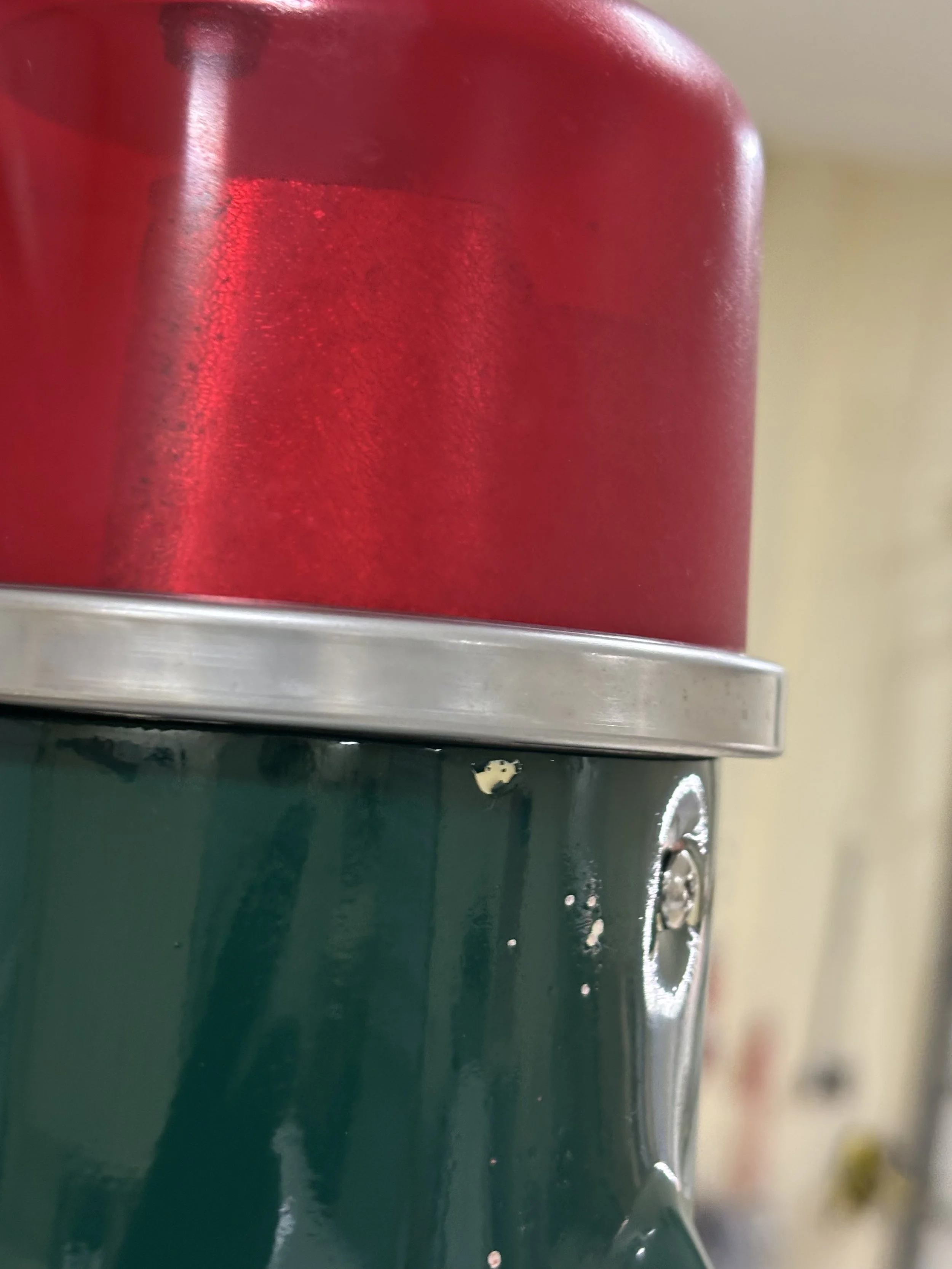 Close-up of a vending machine with red and green sections, showing metallic buttons and a coin slot.