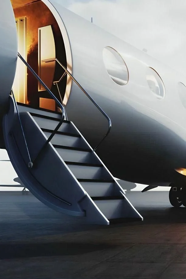 Close-up of a private jet with a staircase leading to the open door, showing the onboard lighting and airplane windows.