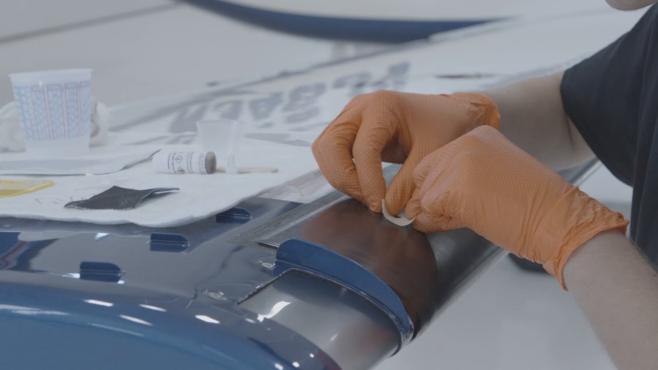 Gloved hands applying treatment to an aircraft de-ice boot.