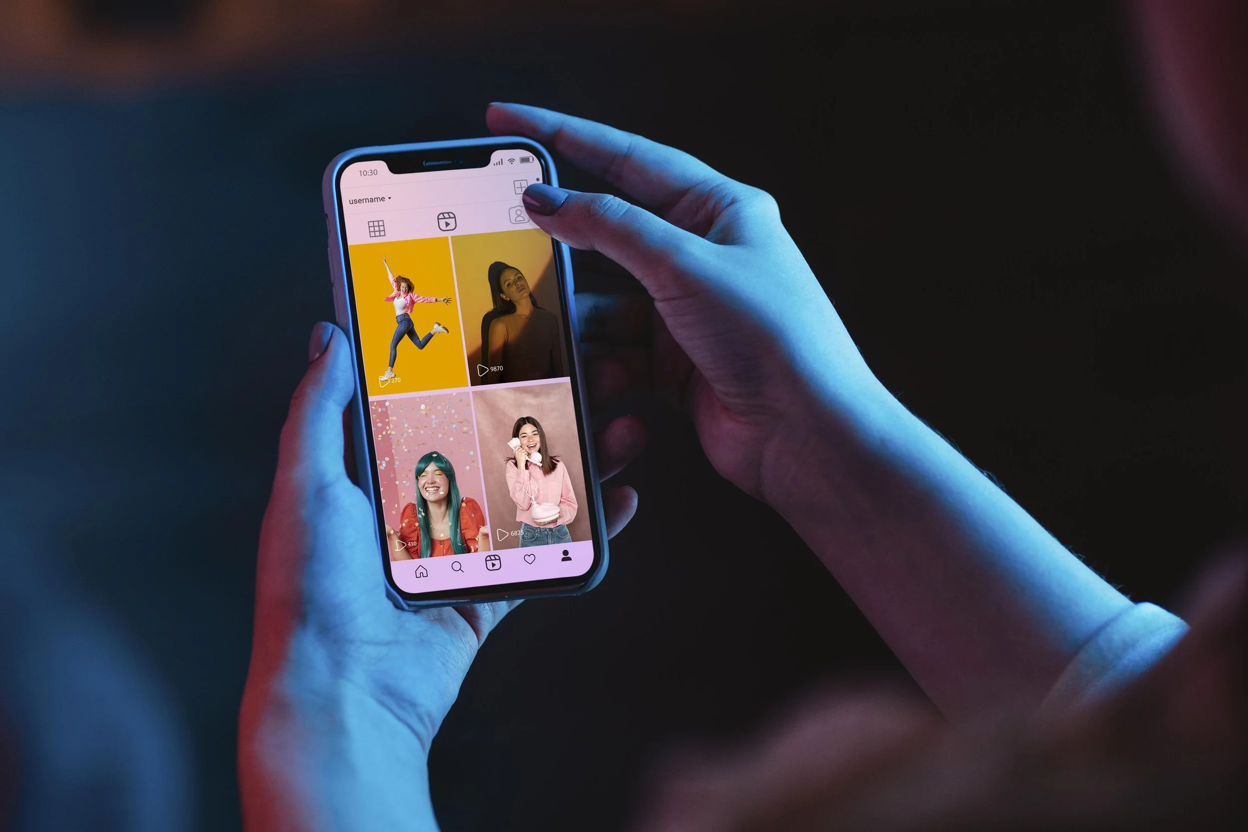 Person holding a smartphone with a social media app open, displaying four photos of women in colorful settings.