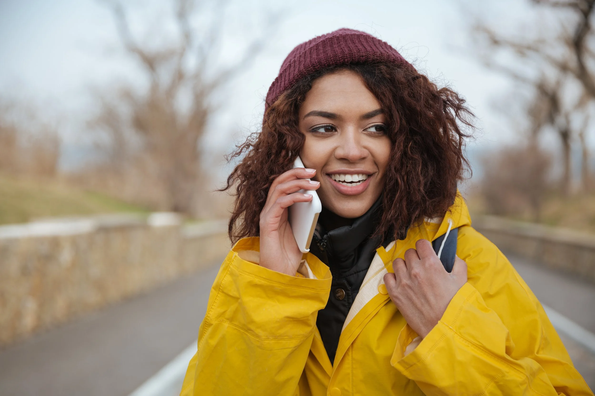 Woman in yellow raincoat talking on cell phone outdoors