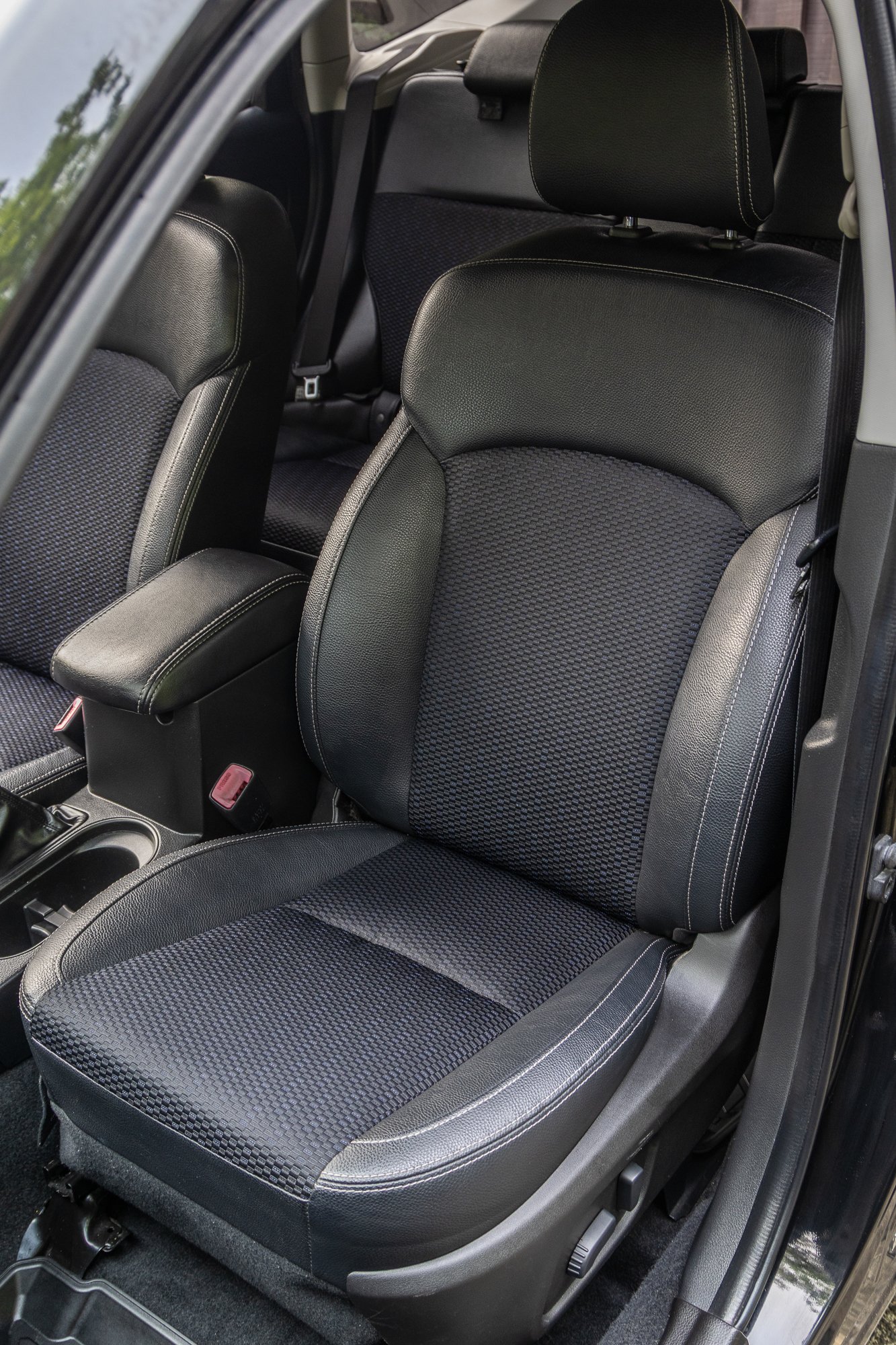 Front passenger seat of a car with black leather and fabric upholstery.