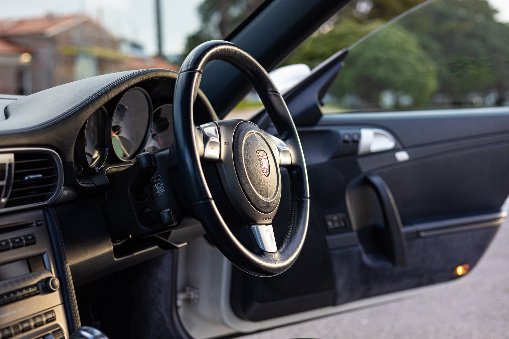 Interior of a Porsche car showing the steering wheel, dashboard, and part of the door.