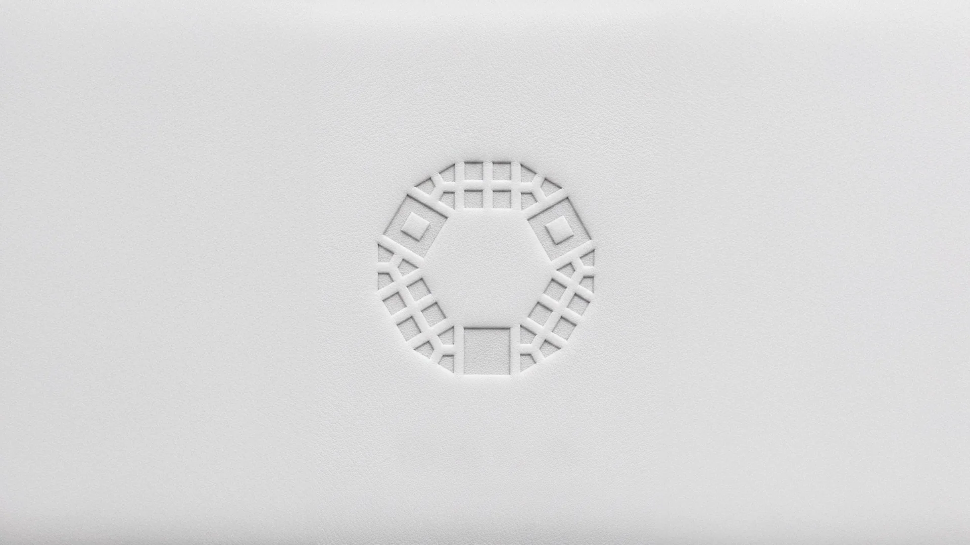 Close-up of a circular ventilation grille with a geometric pattern on a white surface.