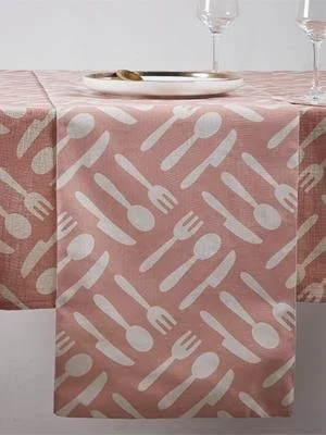 A table with a pink tablecloth featuring white fork, knife, and spoon pattern, set with a white plate and two wine glasses.