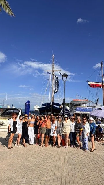Group of people standing on a pier near boats at a marina on a sunny day.