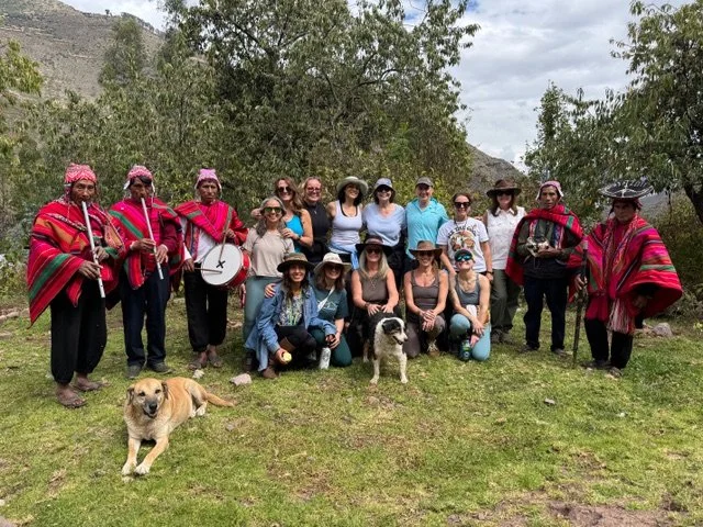 Group of people, including musicians in traditional clothing, posing outdoors with dogs.