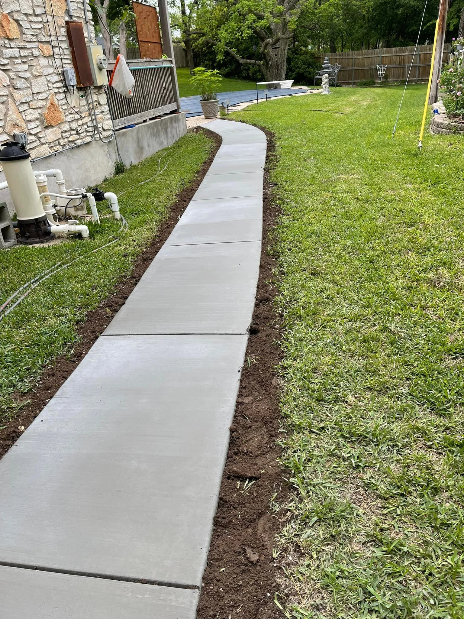 Newly laid concrete sidewalk next to a grassy yard.