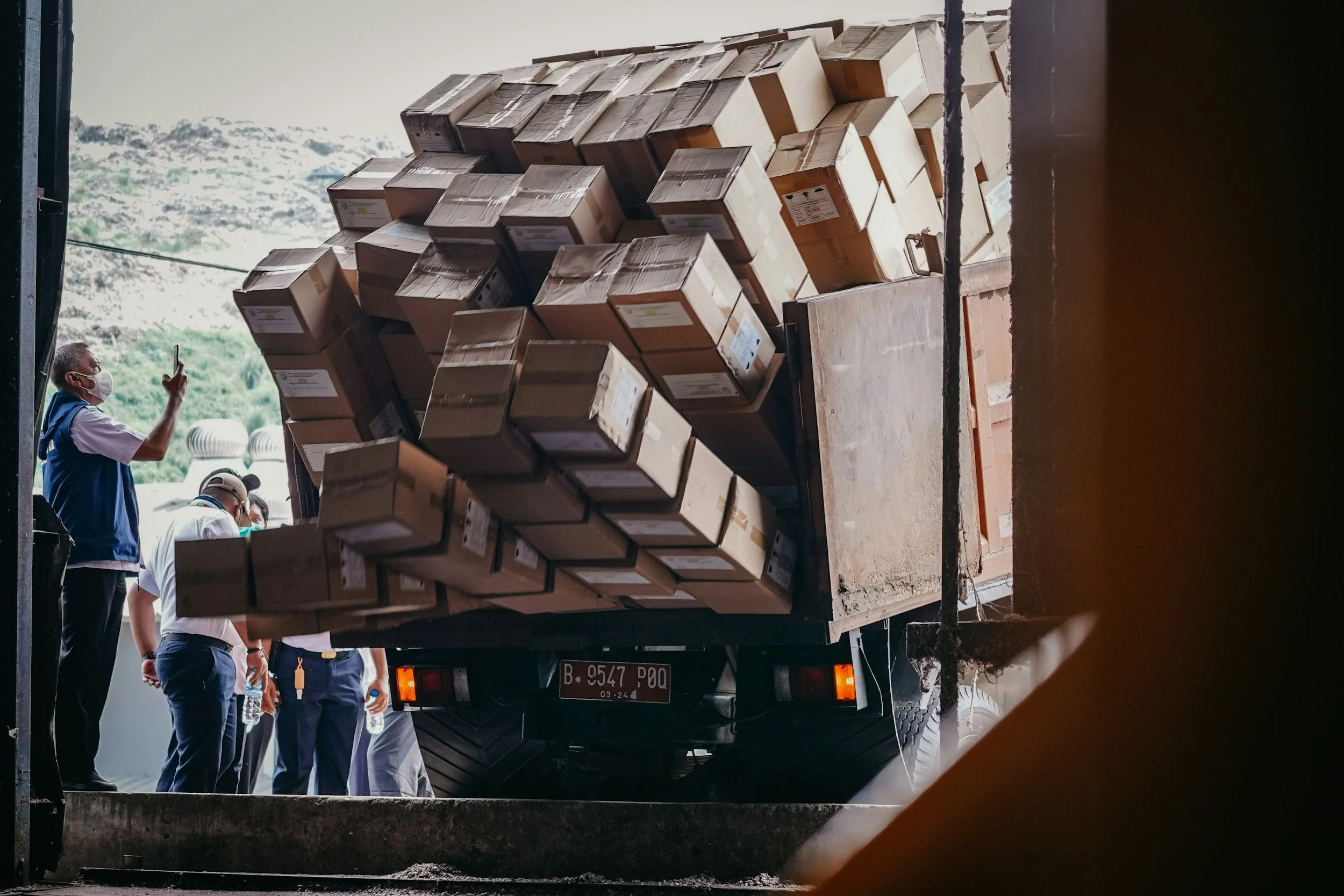 People wearing face masks loading or unloading a truck filled with boxes.