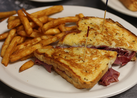 Grilled cheese sandwich with French fries on a white plate.
