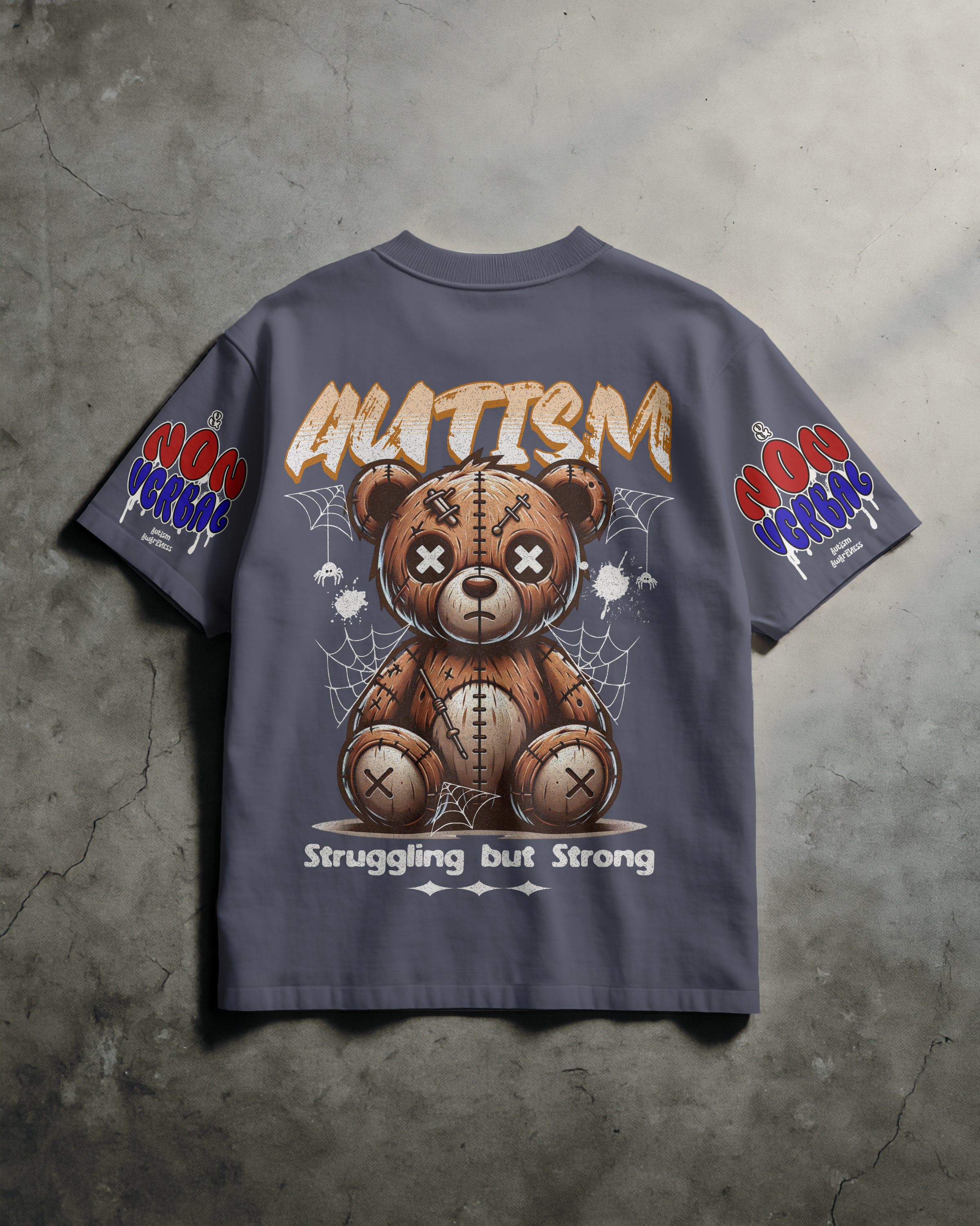 Gray T-shirt with a graphic of a patchwork teddy bear surrounded by spider webs, featuring the text 'AUTISM' at the top and 'Struggling but Strong' at the bottom, with colorful text on the sleeves.