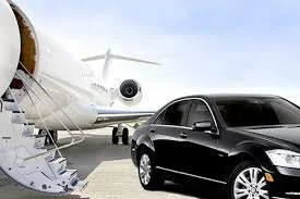 A black luxury car parked near a private jet on an airport tarmac.