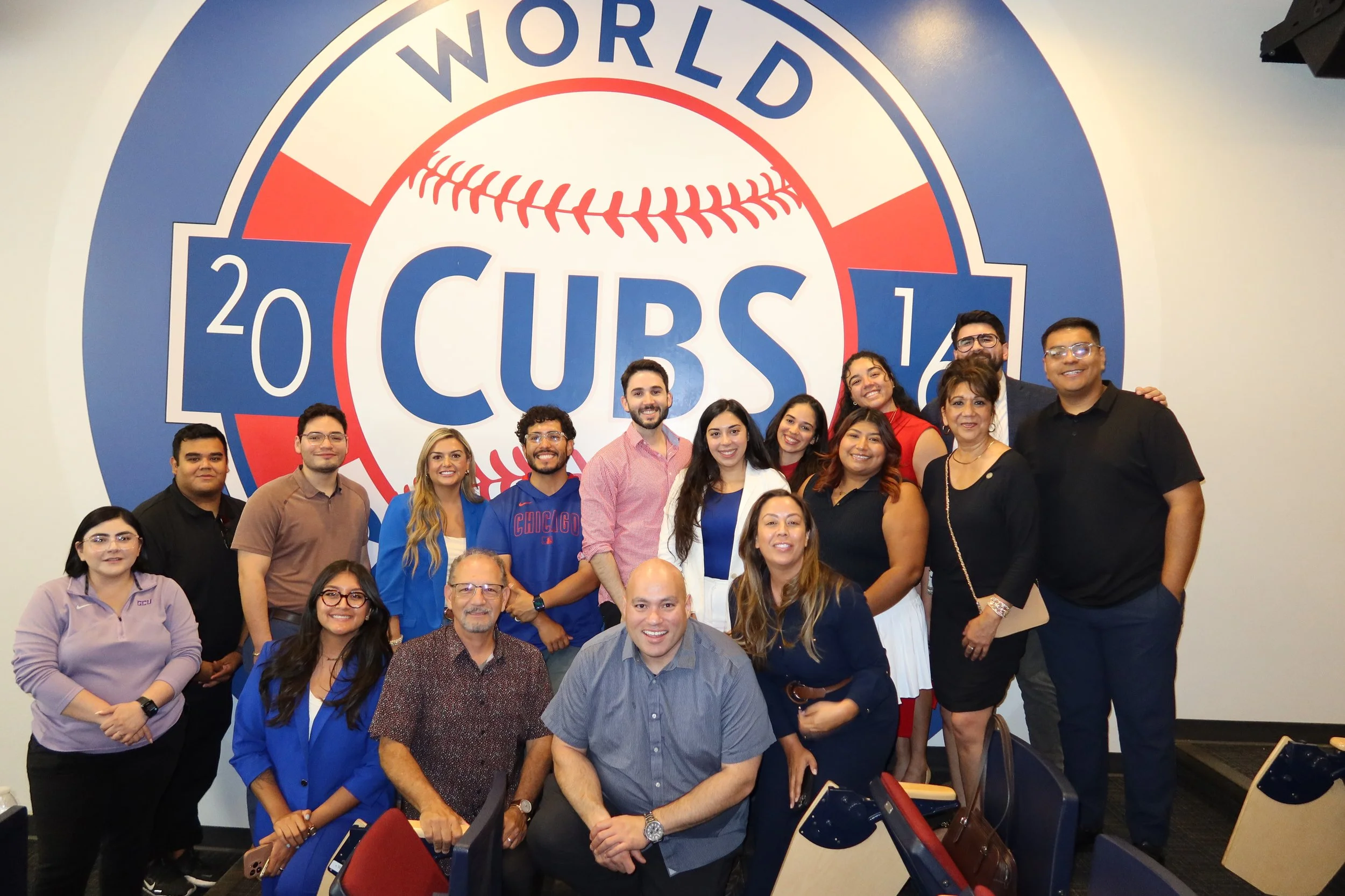 Group of people posing in front of a large '2023 World Series Cubs' logo wall.