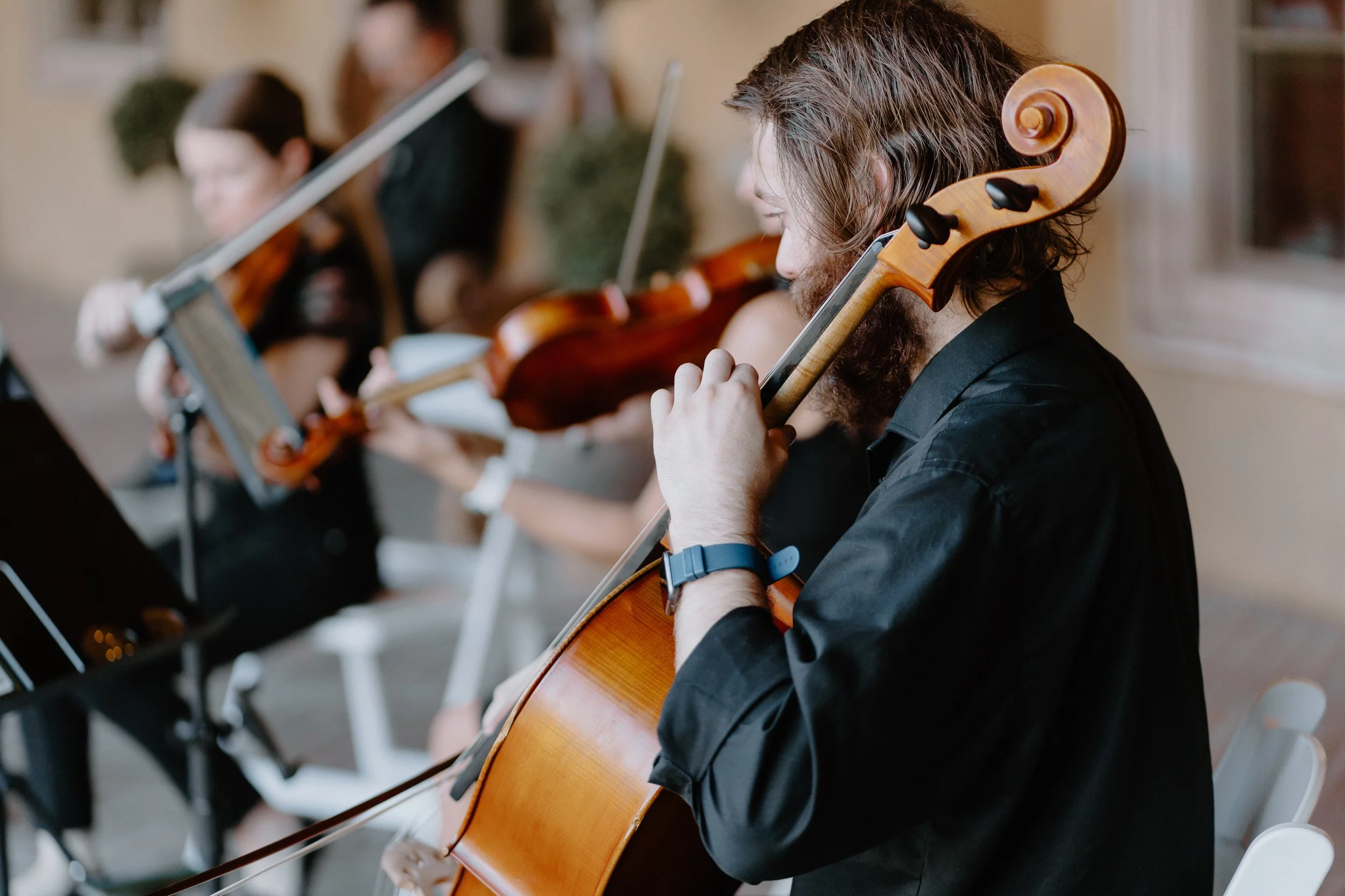 A group of musicians playing string instruments during an indoor rehearsal or performance.