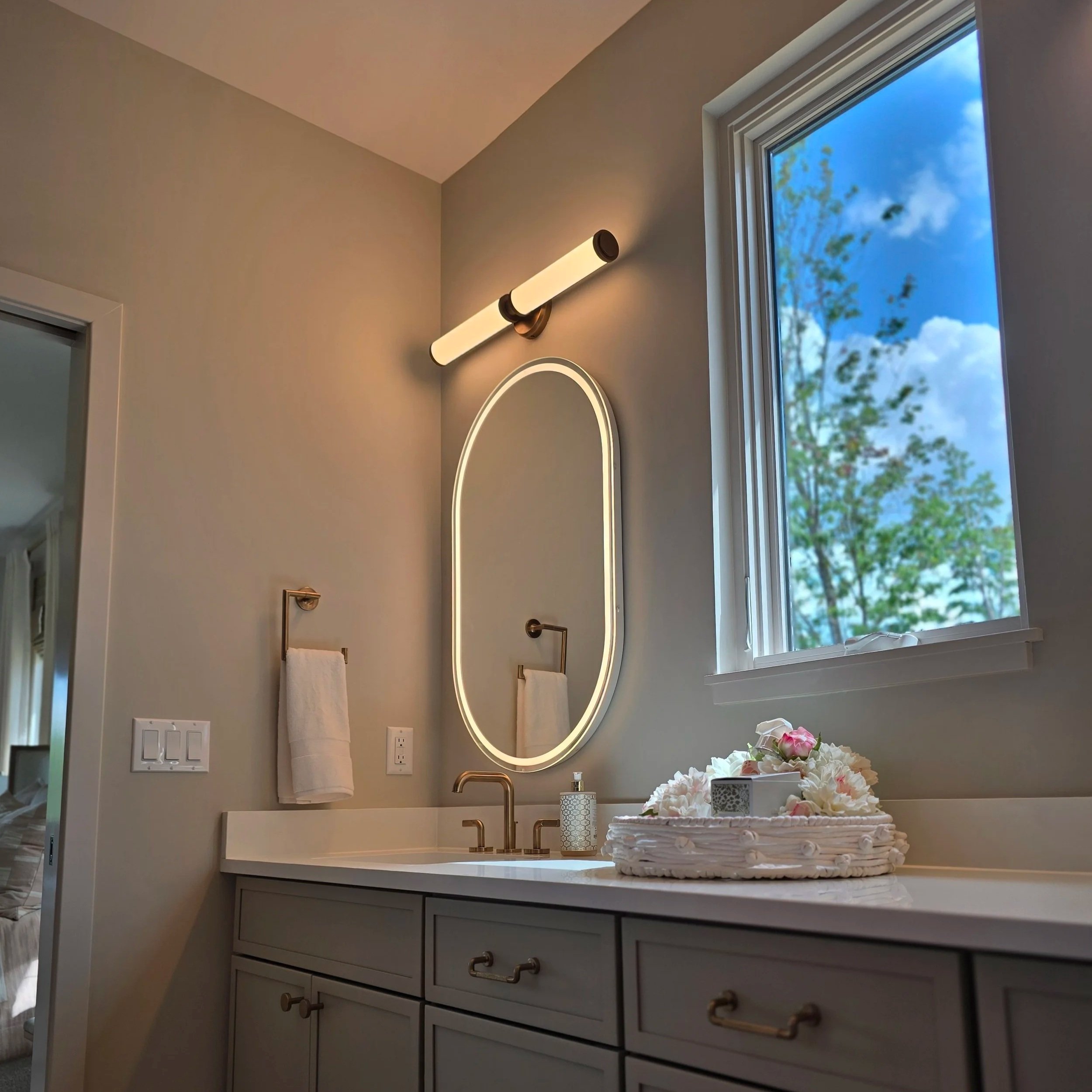 Modern bathroom vanity with professionally installed wall-mounted light fixture and mirror, delivering even, glare-free lighting for functional daily use.