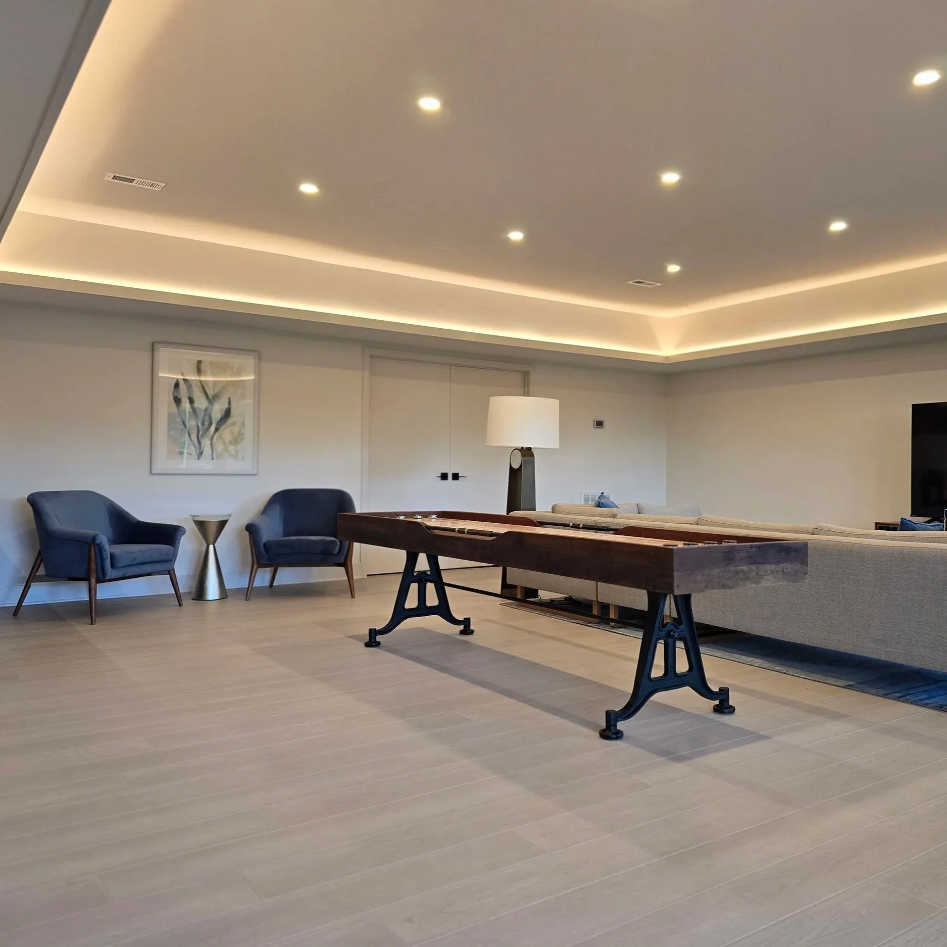 Contemporary living room with recessed ceiling lights and indirect cove lighting, showcasing smooth, balanced illumination enabled by sufficient electrical service capacity.